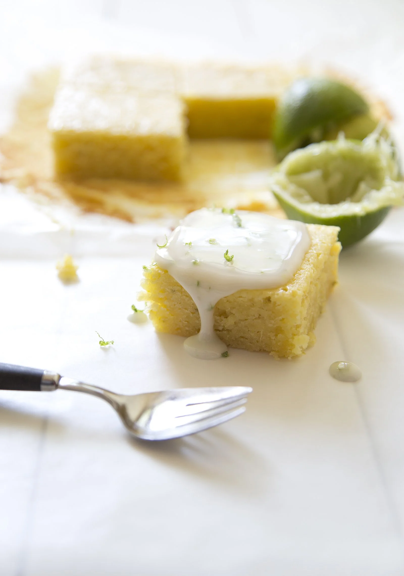 Lime and white chocolate lemons on white wooen table top, with pressed lime in the background