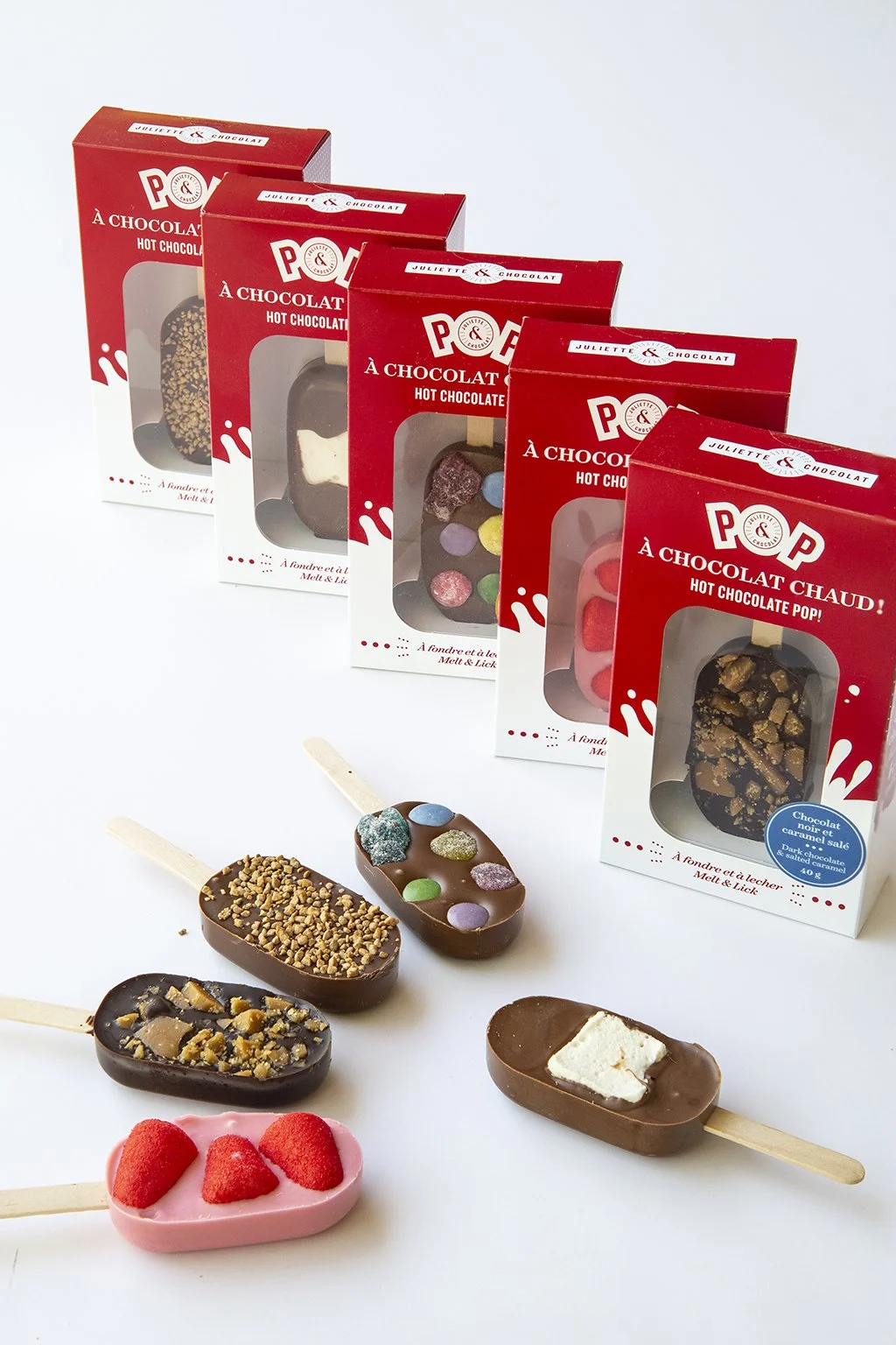 Chocolate lollipops to dip and melt in hot milk, in vibrant red packaging. 