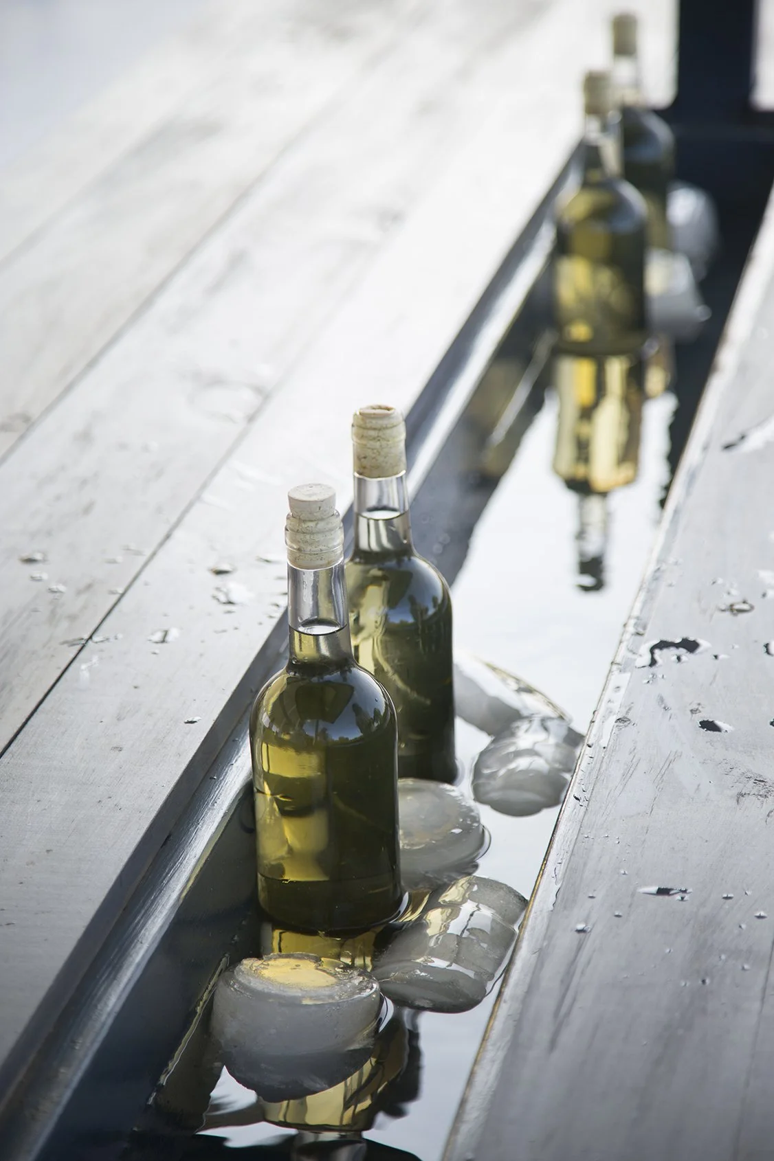 White wine bottles in wooden cooler built in table beautiful light