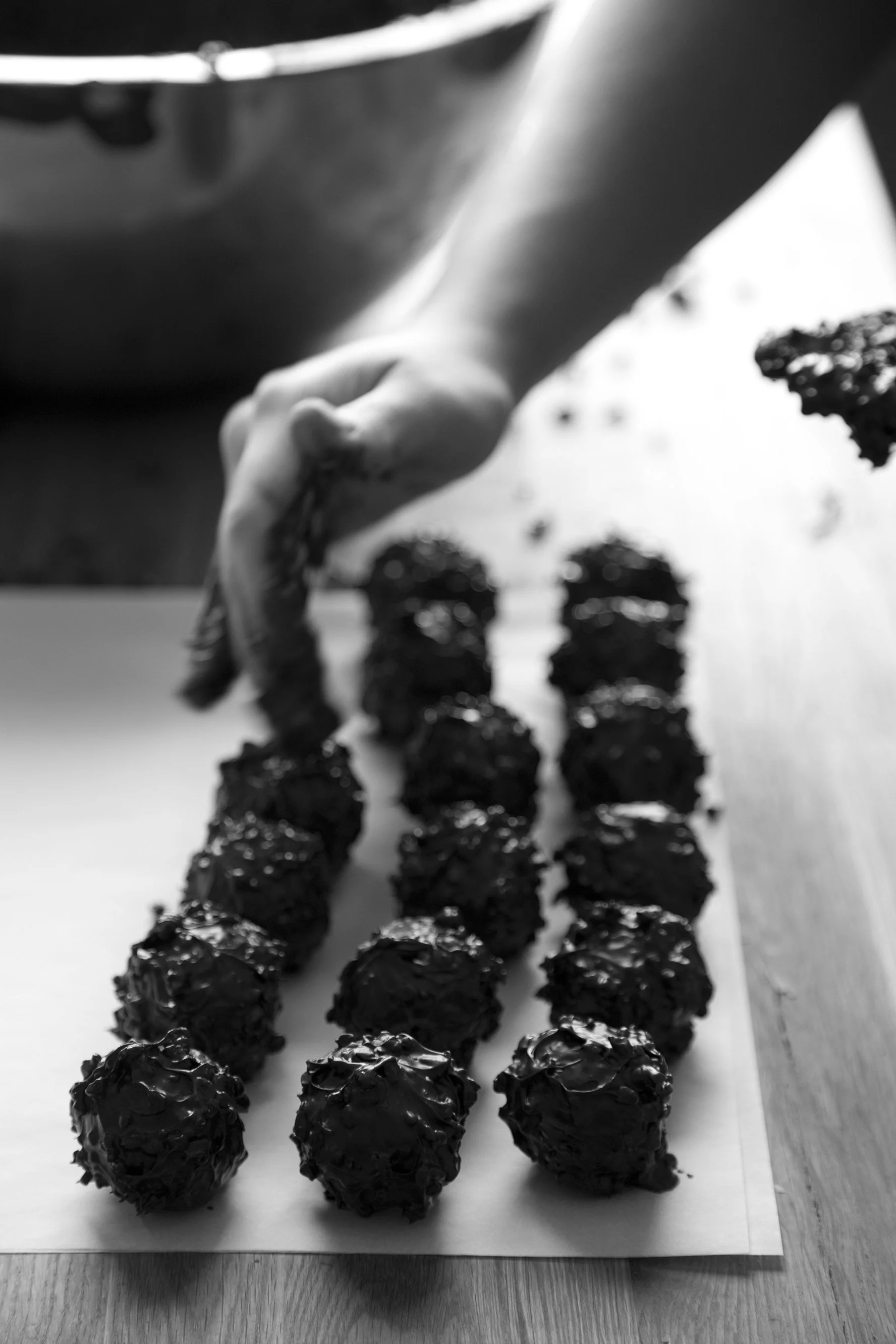Hands forming chocolate confections with crunchy caramelized nuts