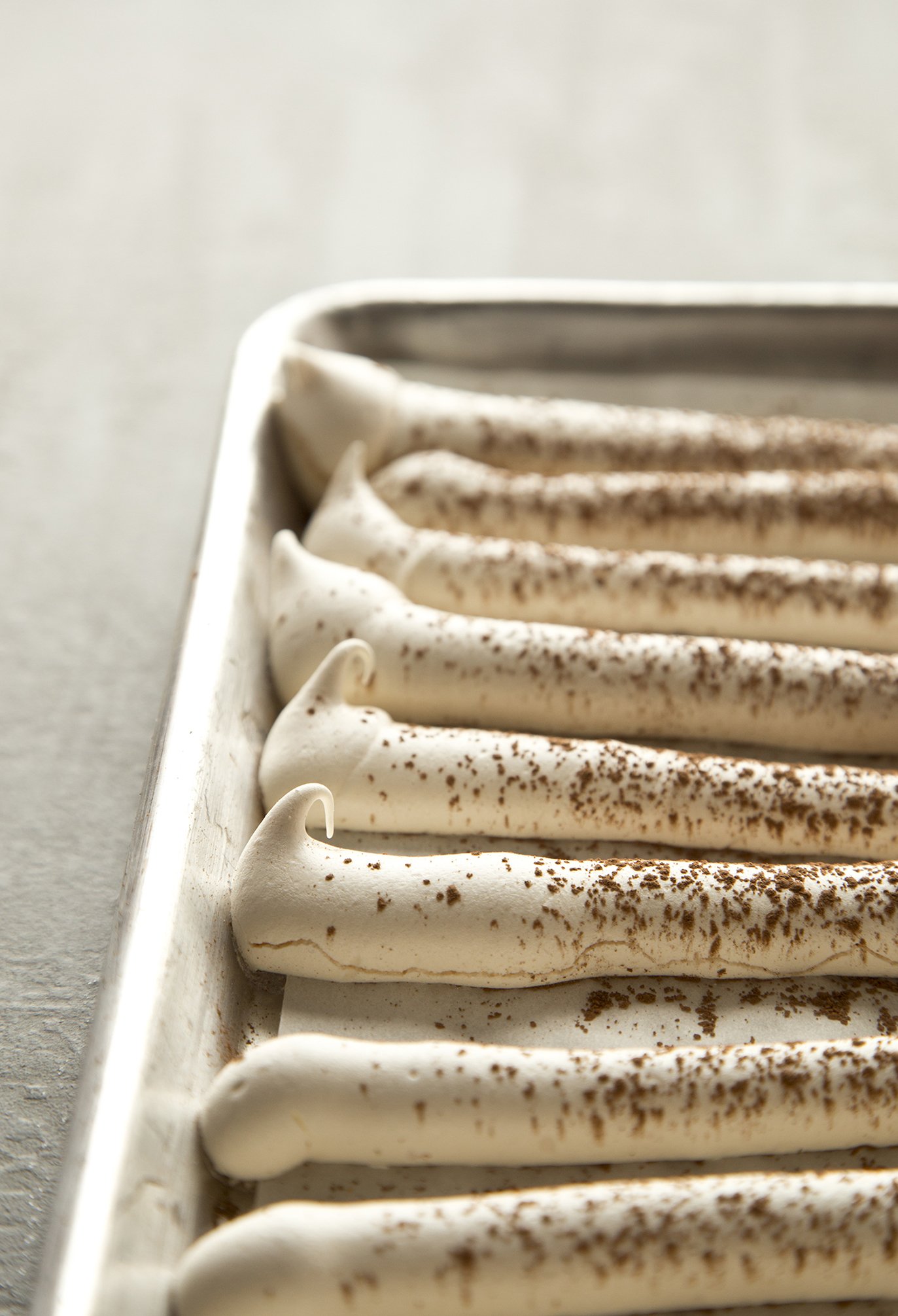 Crunchy meringue strips on cooking tray, dusted with cocoa, fresh out of the oven