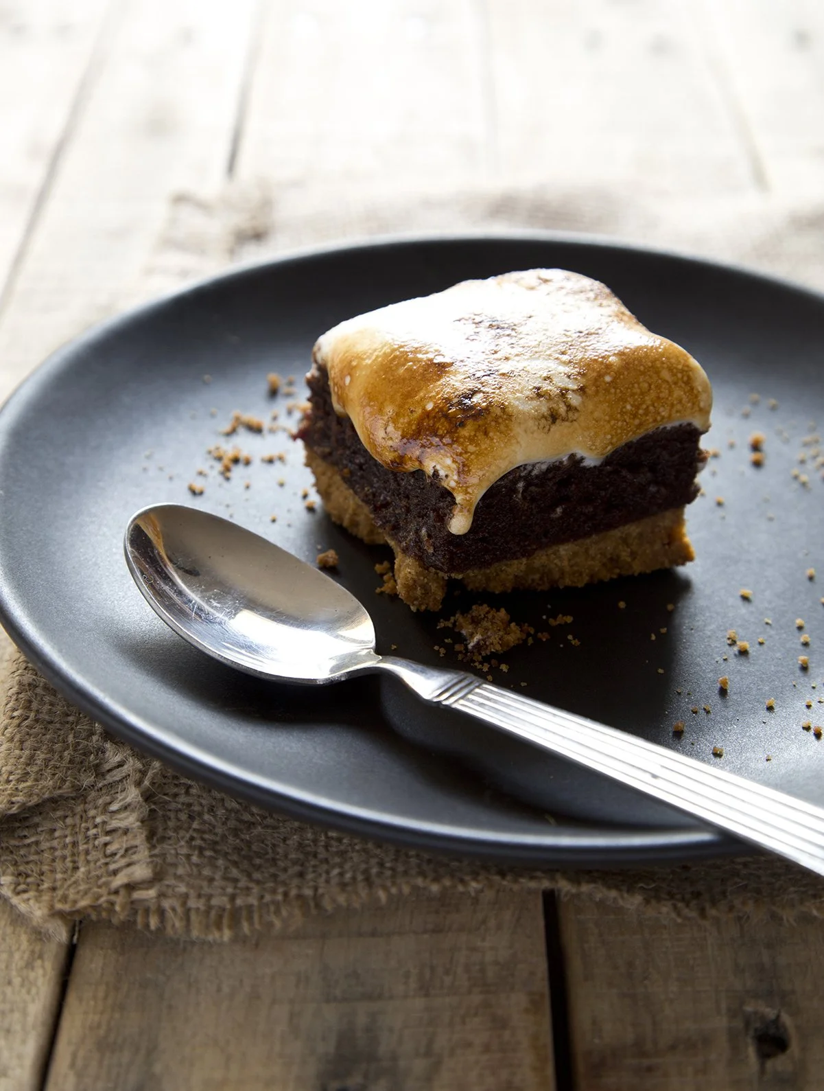 A S'mores brownie on a blue plate, with roasted marshmallow top.