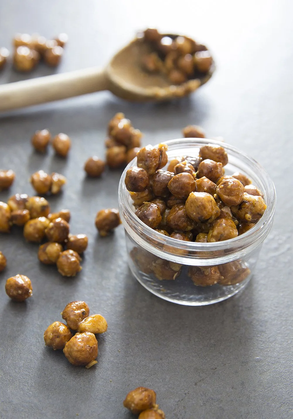 Roasted caramelized hazelnuts in jar, with wooden spoon, golden shiny caramel crust on nuts