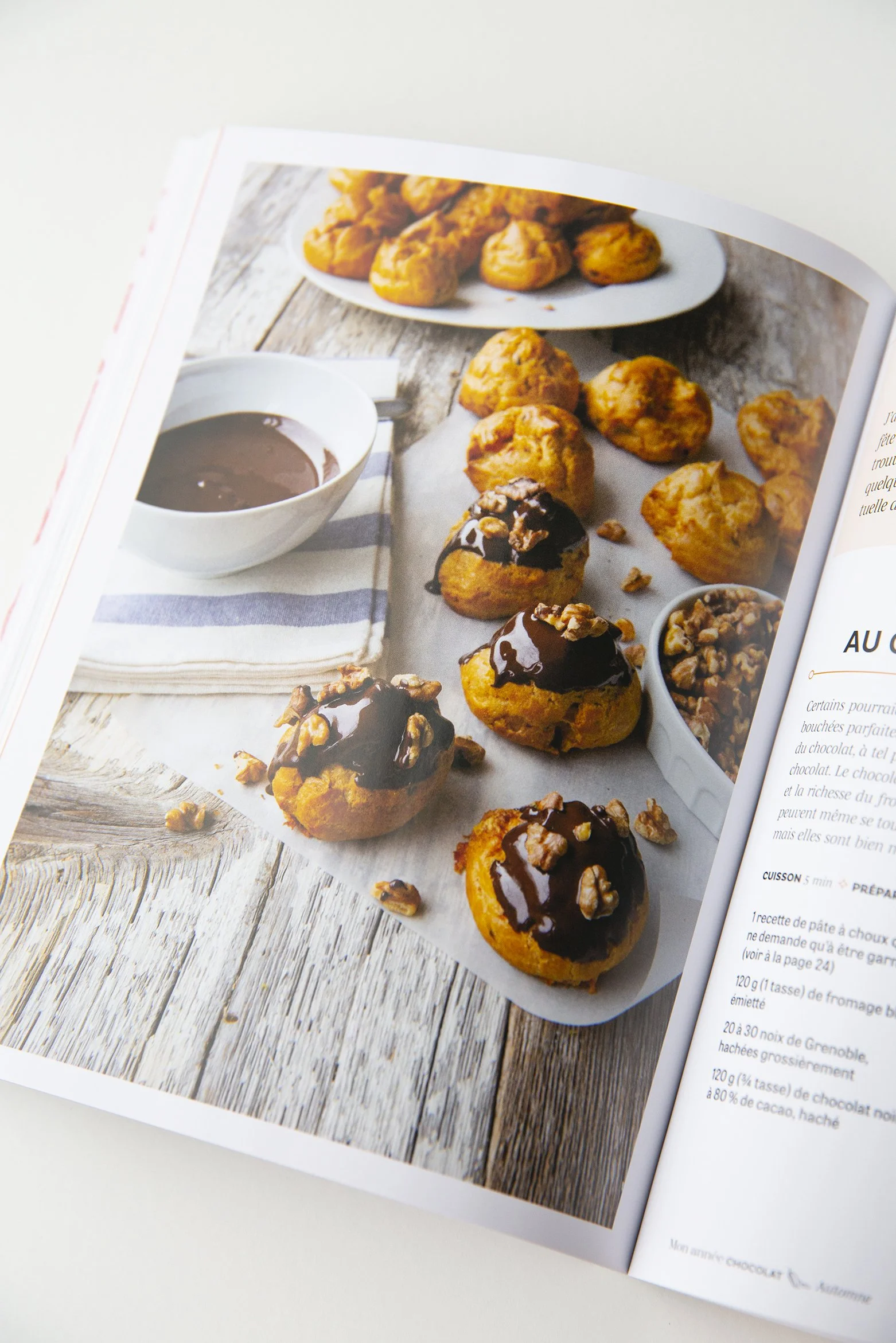 Profiteroles in an open cookbook showing a double page with a profiterole recipe and a beautiful photo.