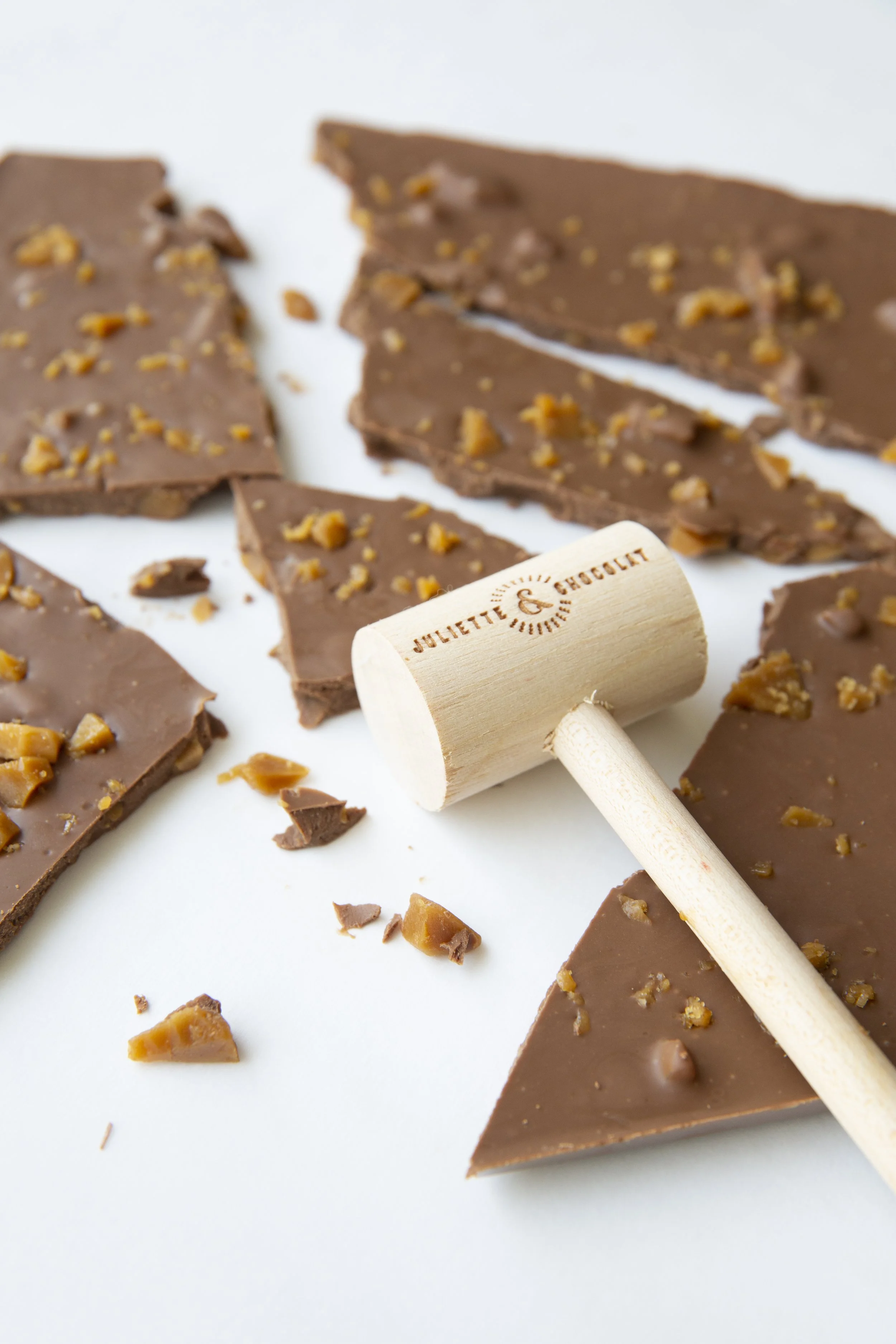 Broken milk chocolate and caramel bar with wooden mallet inscribed Juliette & Chocolat.