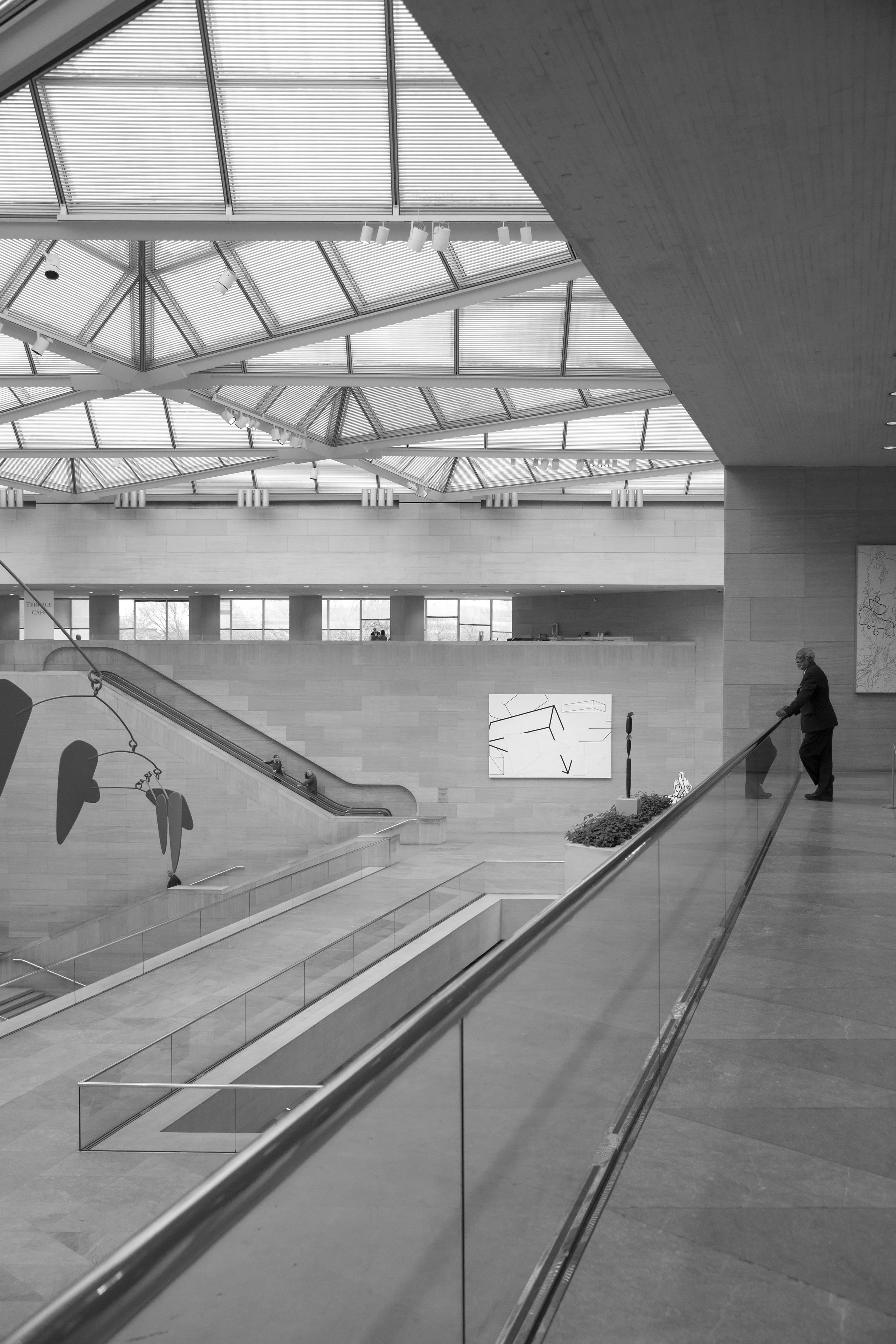 Modern architecture, black and white view of art museum with dramatic perspective and glass ceiling above stone floors. 