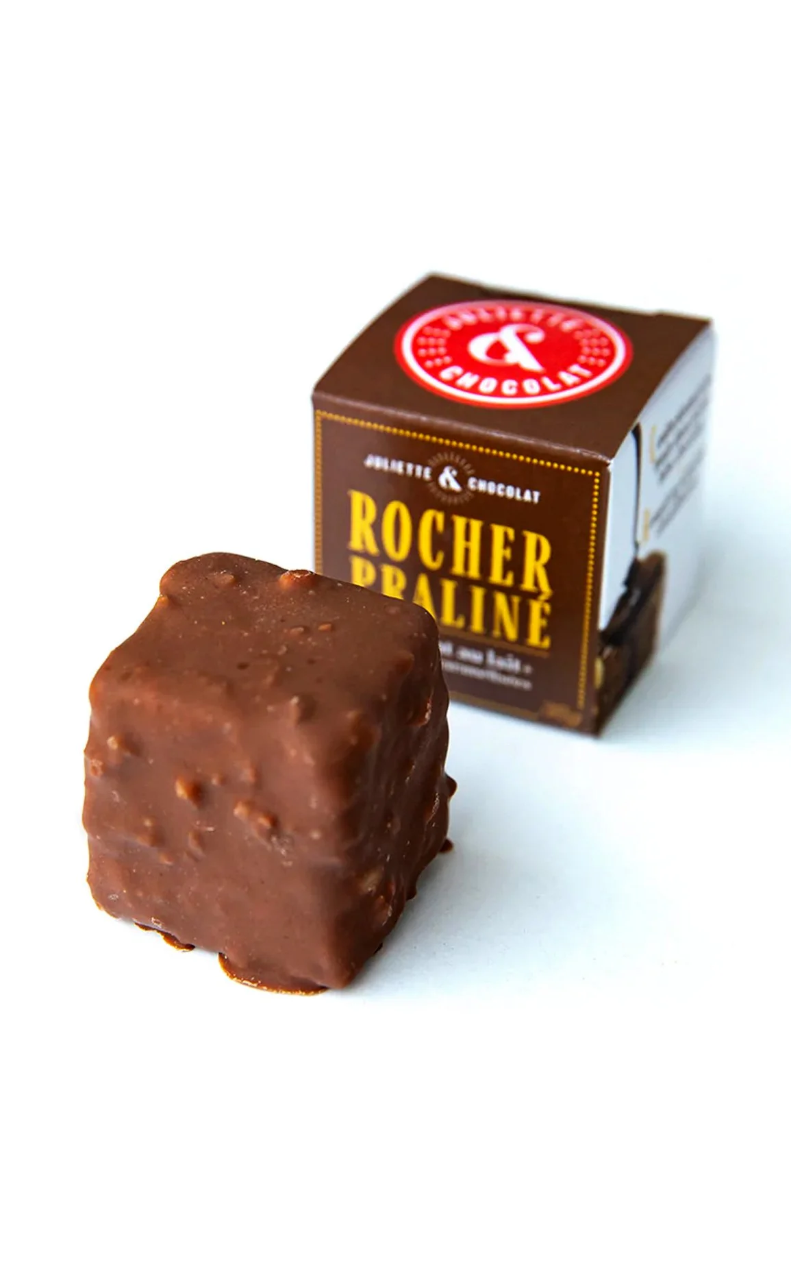 Crunchy milk chocolate cube with roasted hazelnuts in front of small box with name and logo