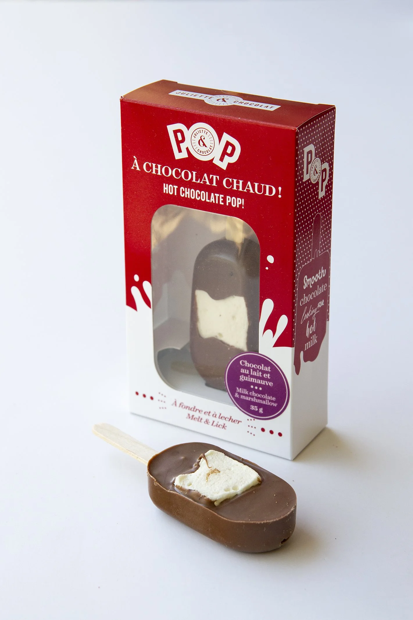 Milk chocolate lollipop with marshmallow, displayed with its red packaging.