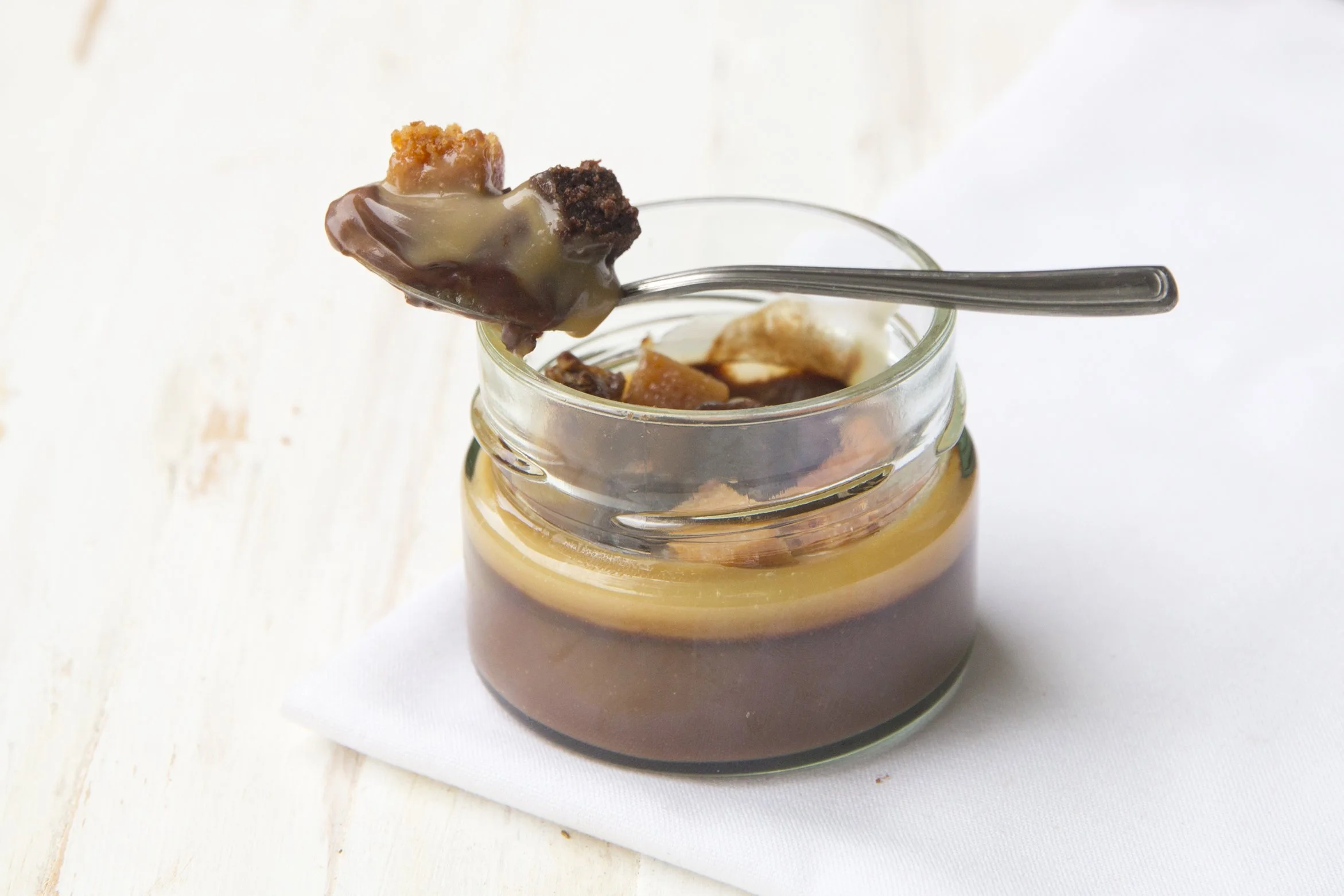 Chocolate mousse and slated caramel in a jar, with spoon and dripping caramel
