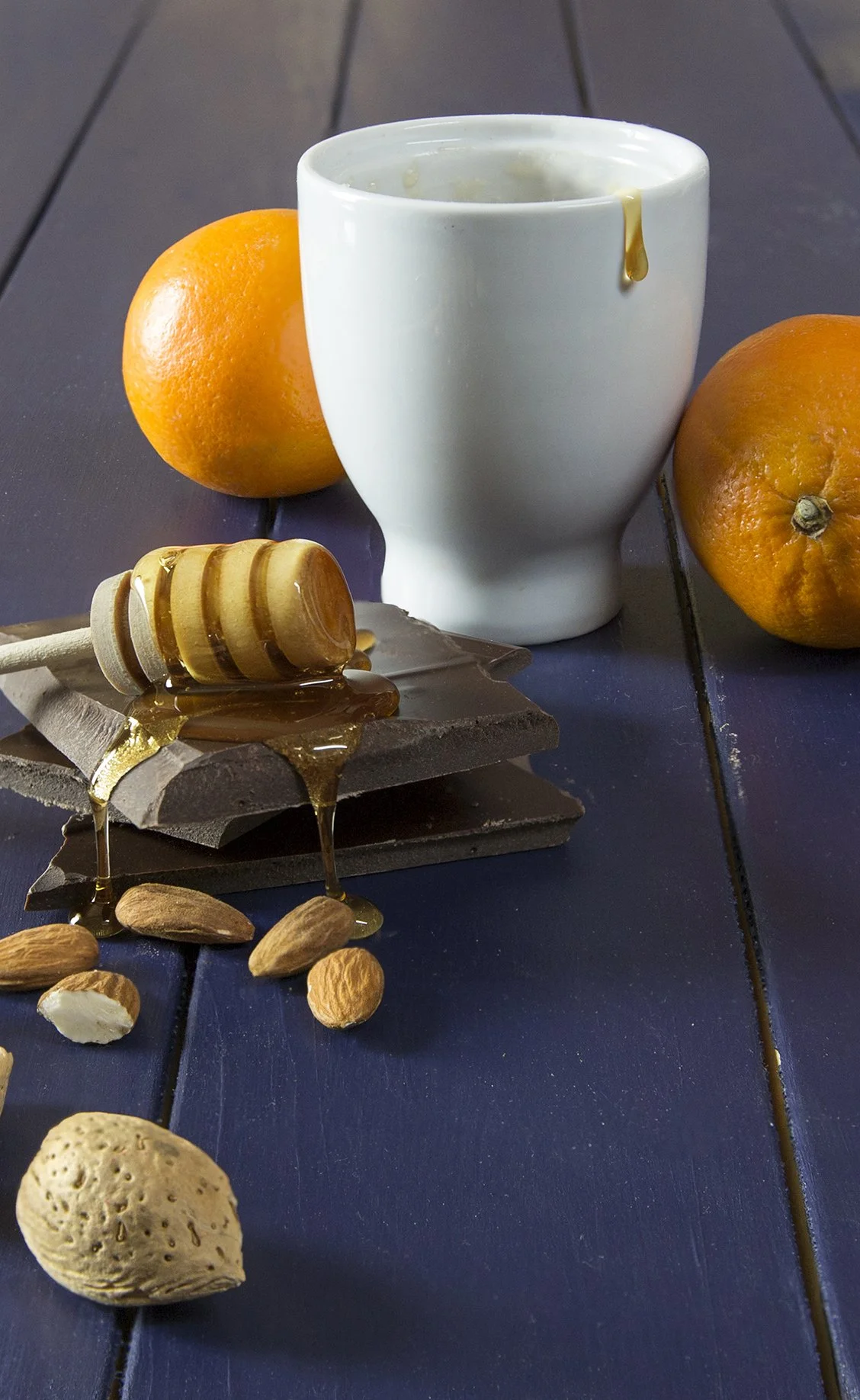 Dark chocolate, honey, oranges and almonds on dark blue background