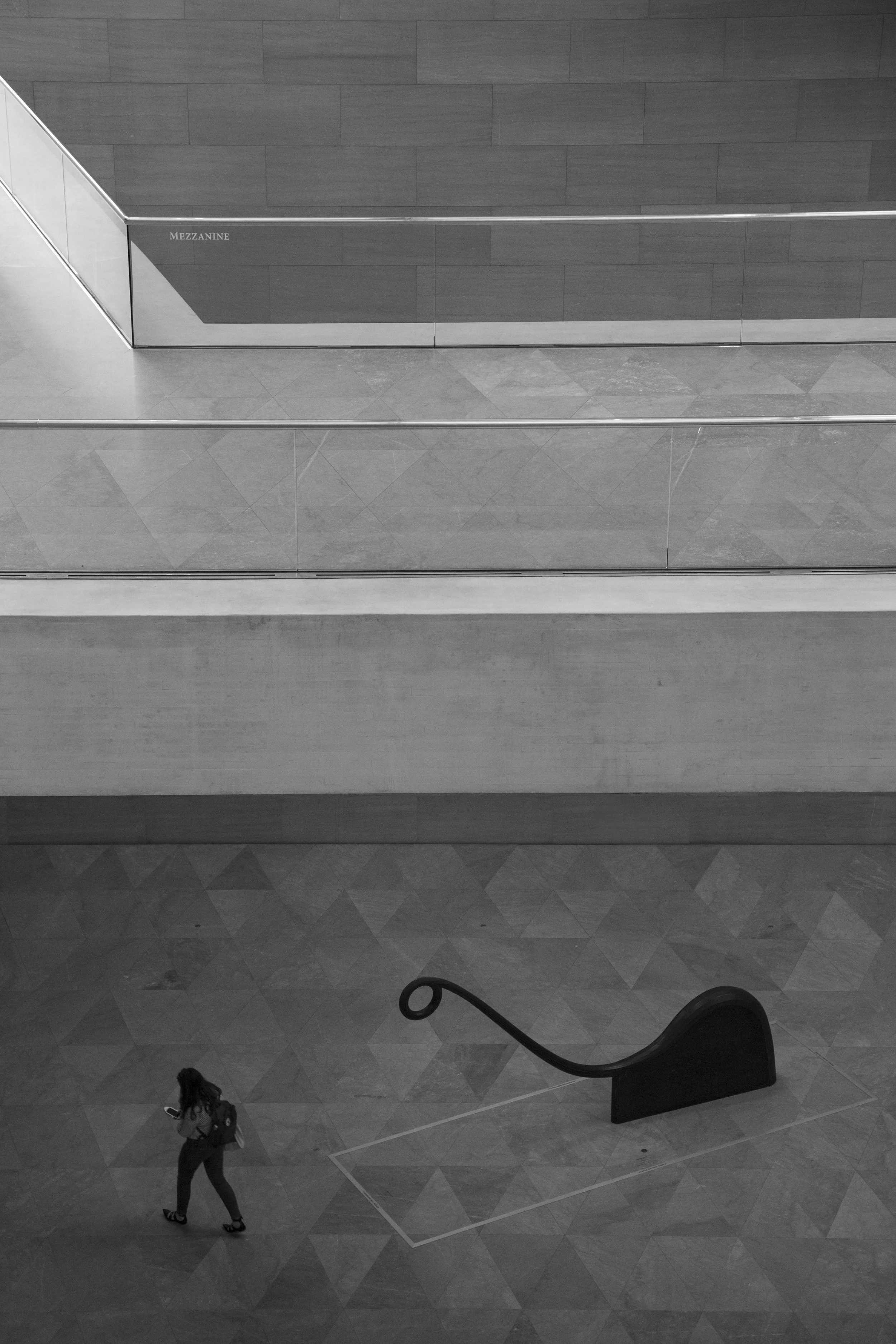 MInimalist and symmetrical view of an art museum, black and white photo with art and passerby.