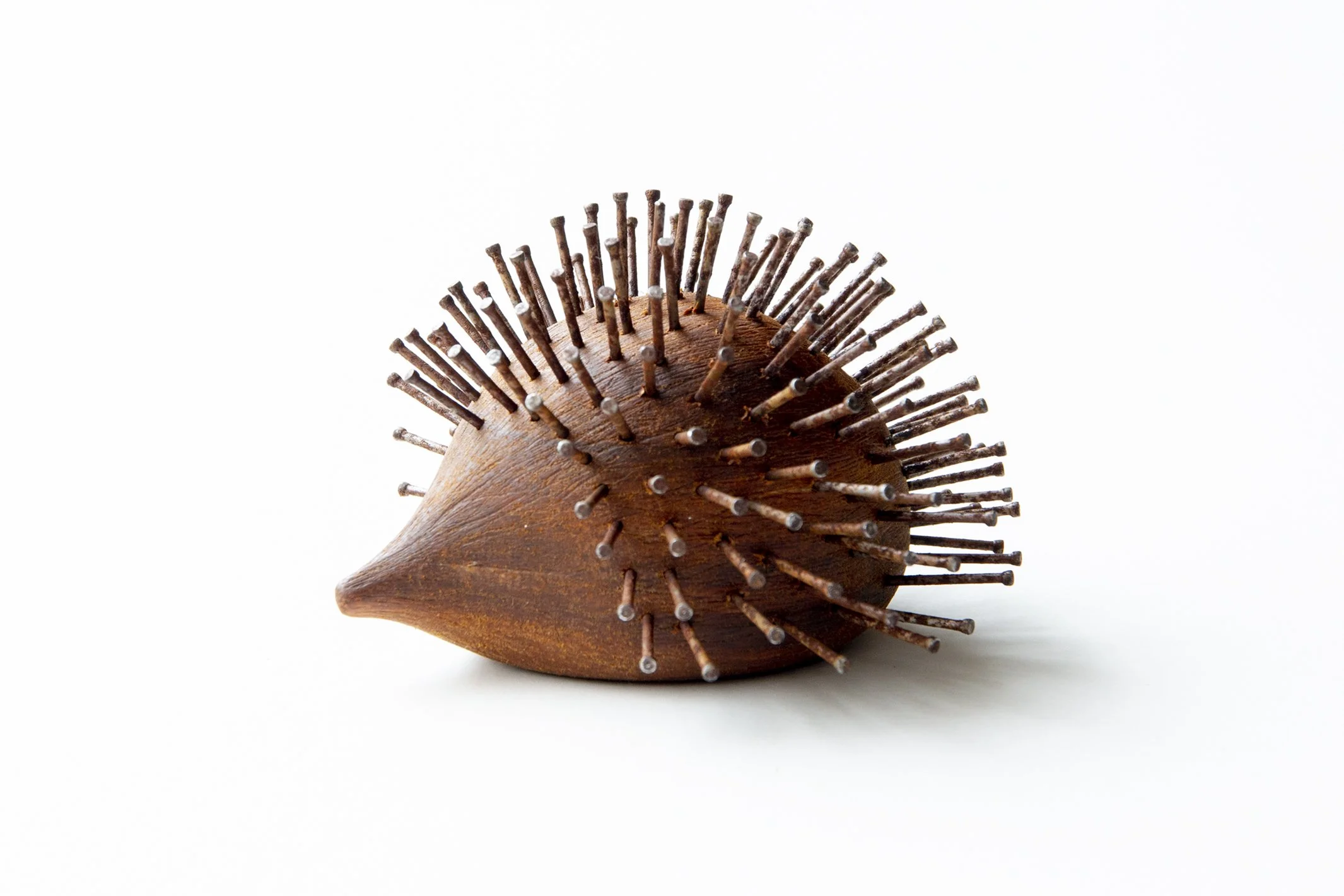 wooden sculpture of hedgehog with rusty nails for quills, by Lionel May
