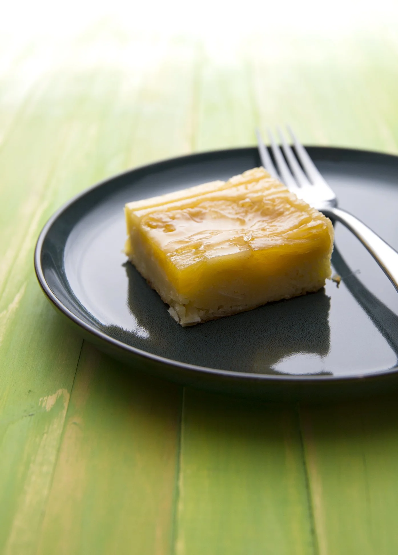 Golden passion fruit brownie on dark plate and green wooen table