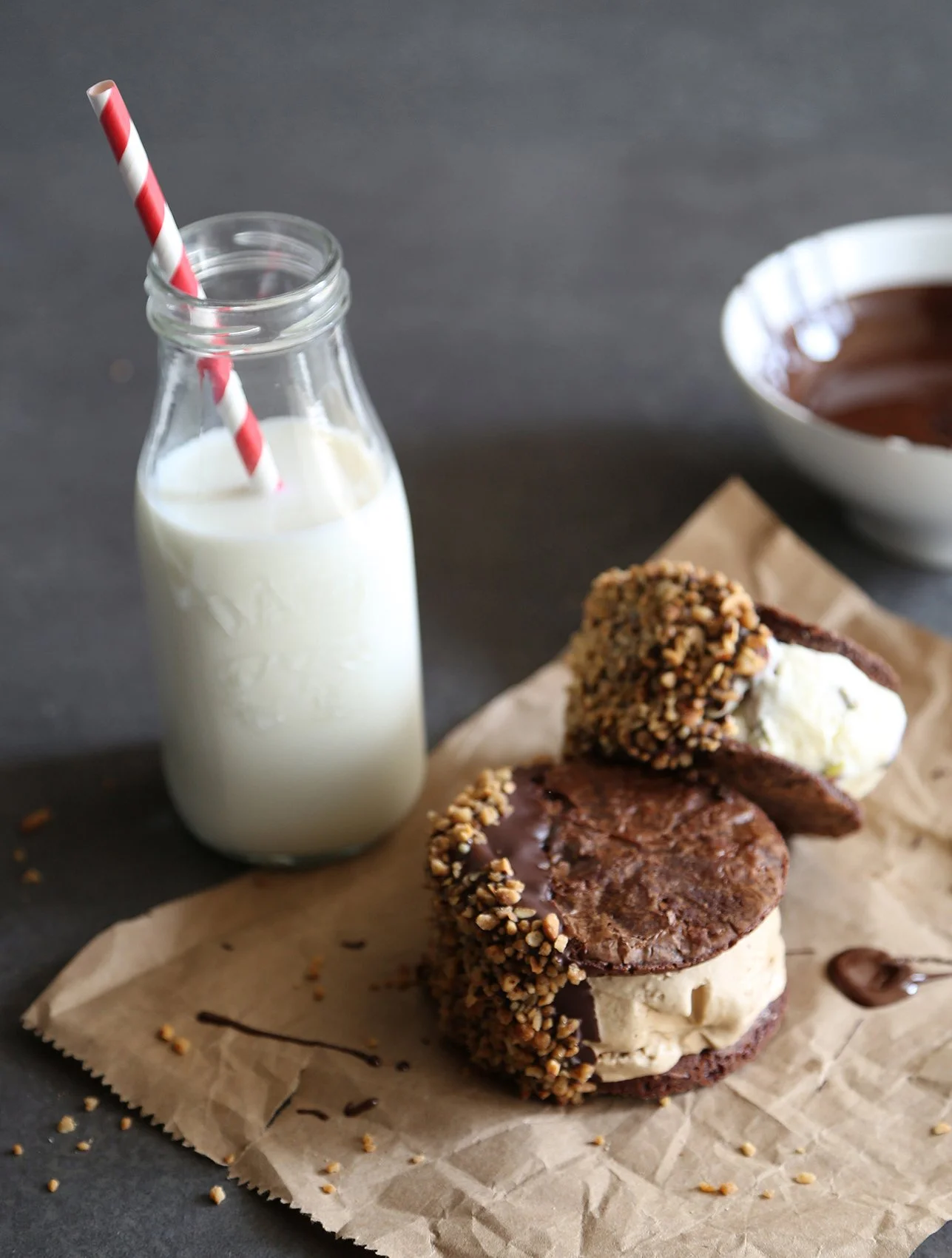 Ice cream sandwiches with vanille ice cream between two thin brownies, dipped in milk chocolate and accompanied by a bottle of milk