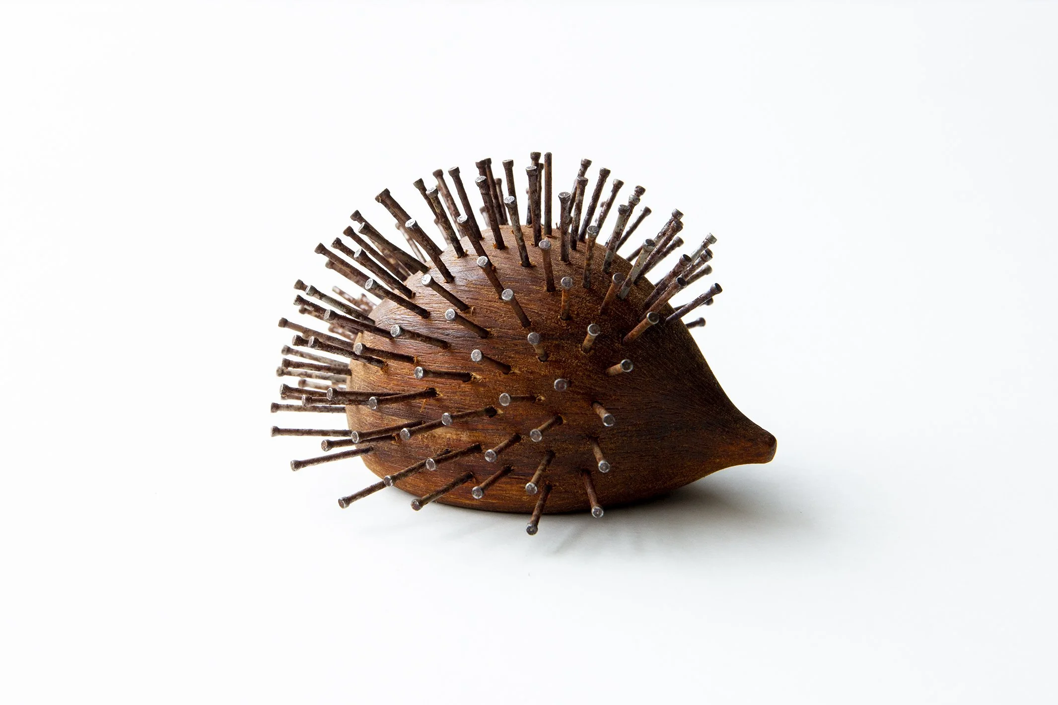 Wood and metal hedgehog sculpture on white background.
