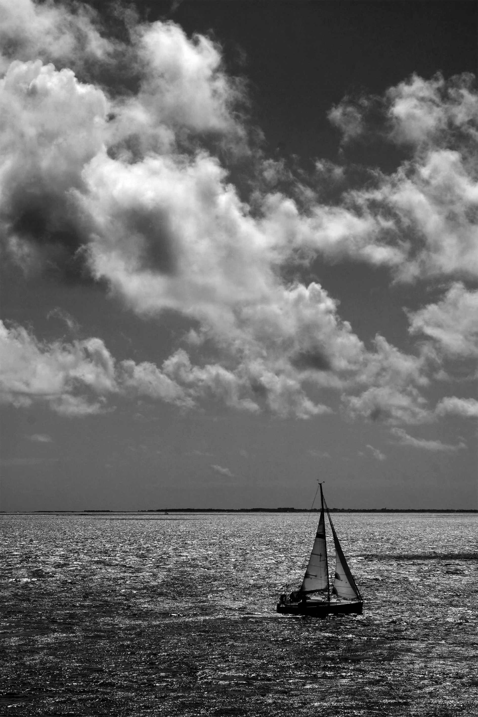 A sailship on the sea, with sunny skies and fluffy white clouds, black and white photograph taken in Bretagne, France. 