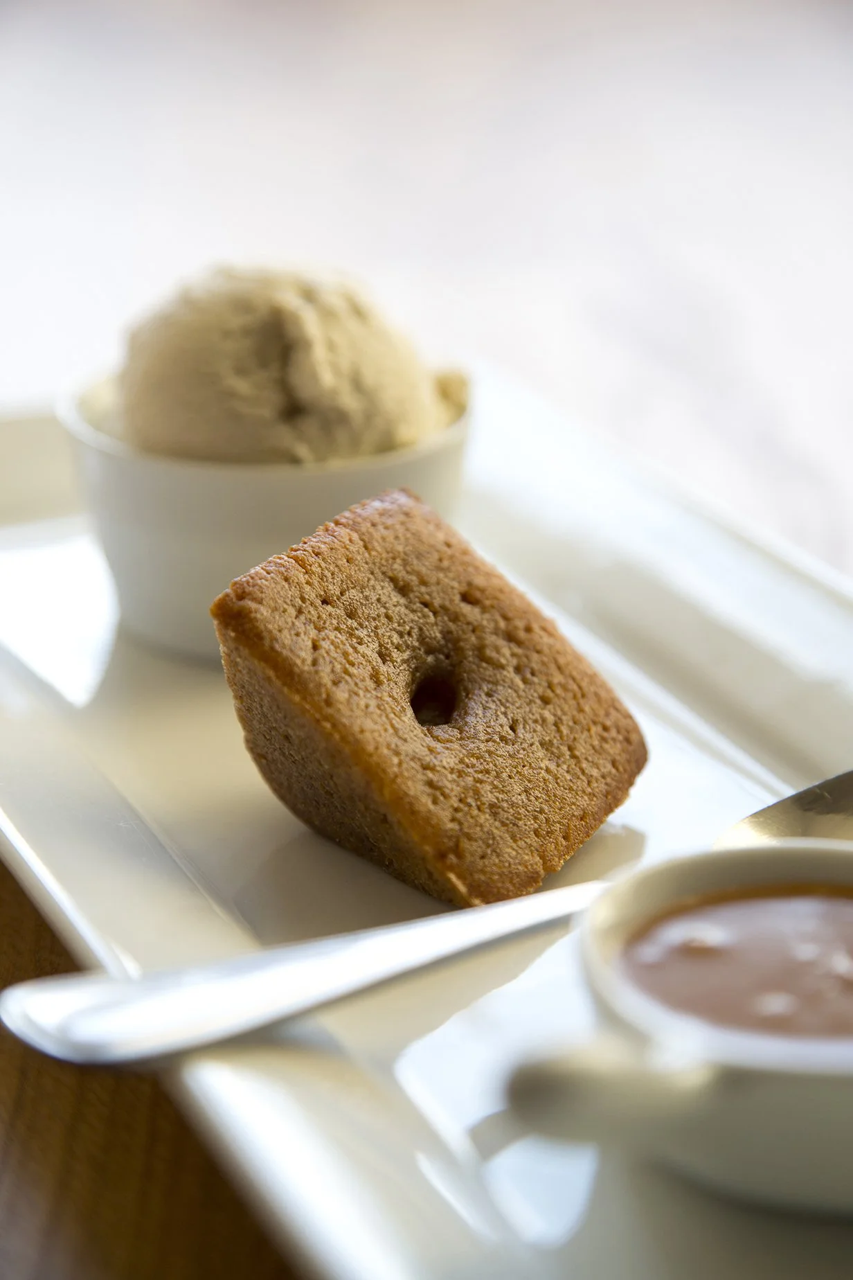 Maple caramel pastry on long serving plate, with a scoop of vanilla ice cream and a small jar of caramel