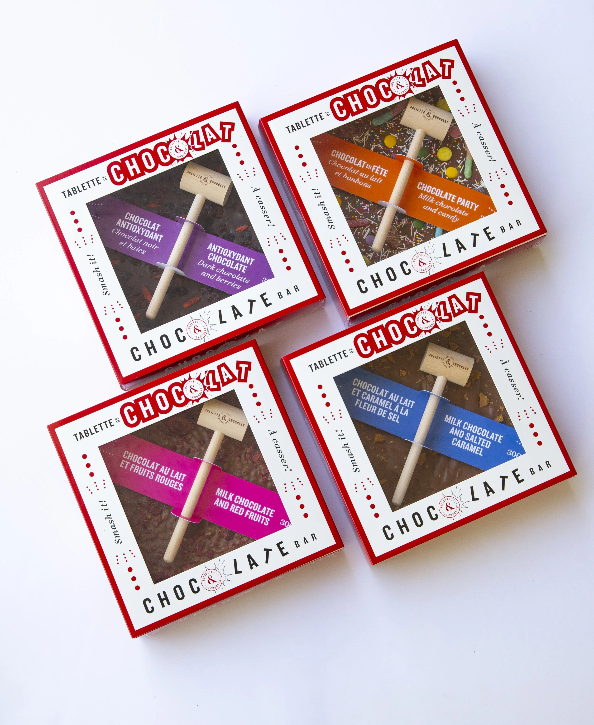 Four chocolate smash bars in colorful sliding boxes that come with wooden hammers to break the bars. 