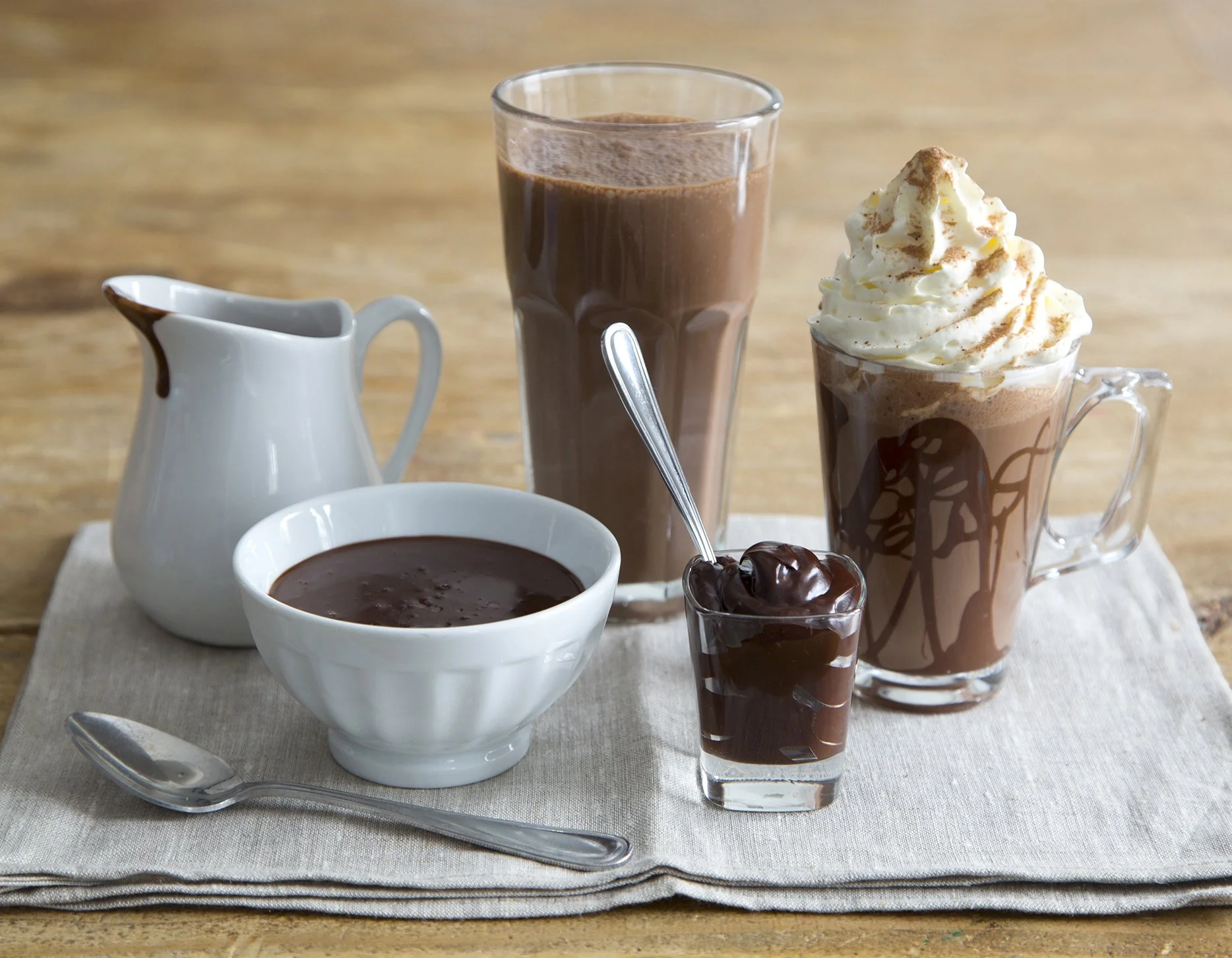 Drinking chocolate, hot and cold, in beautiful dishes different sizes, milkshake, chocolate ganache, and moccachino arranged on beautiful wooden table 