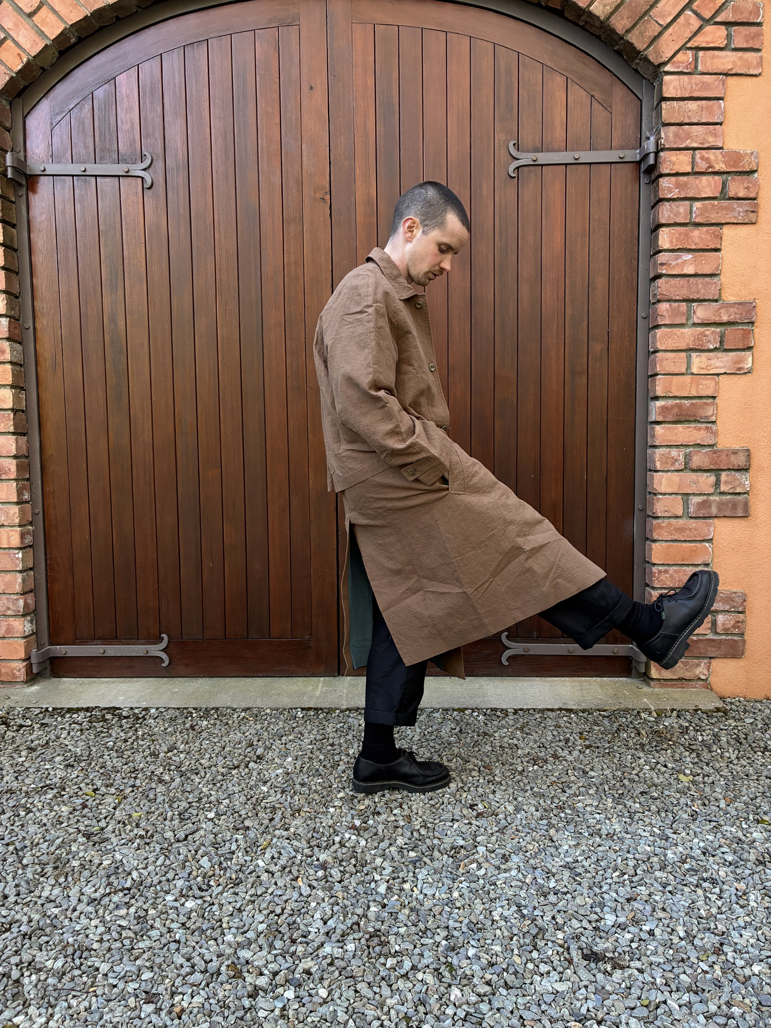 Side of man man in front of door wearing Frank Leder Reversible Coat in Brown and Teal