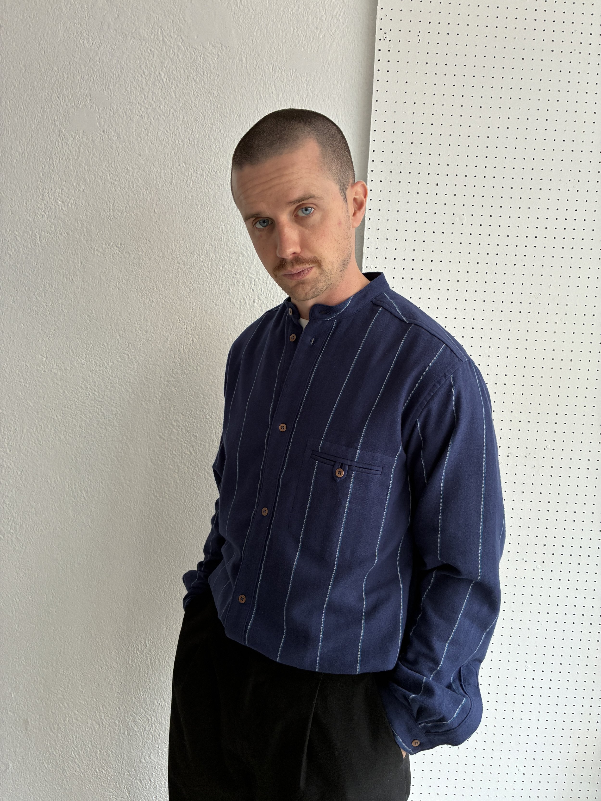Model wears a Frank Leder navy striped shirt, side profile view.
