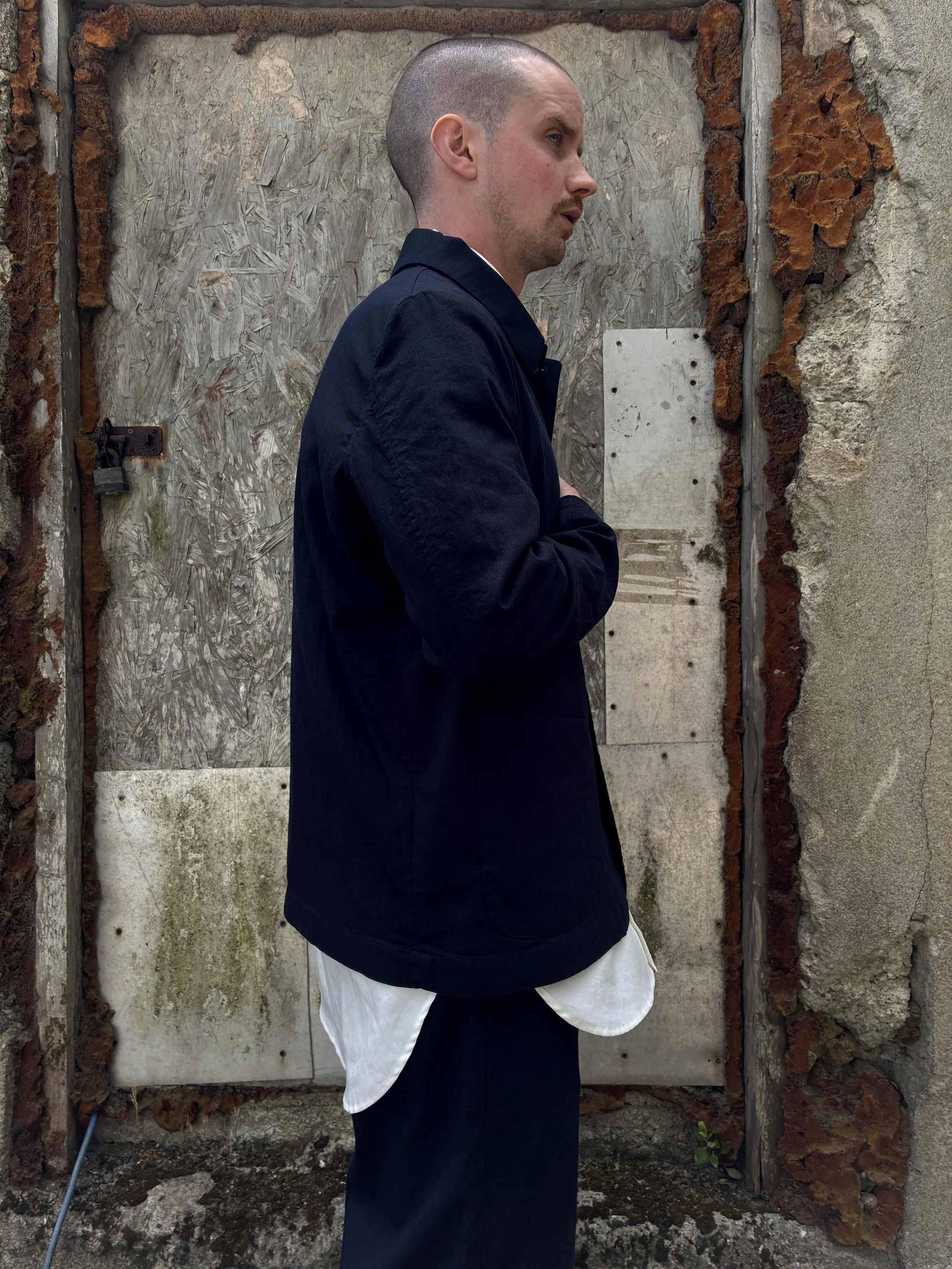 Side of Man in front of wall wearing Navy 1st PAT-RN Notion Jacket