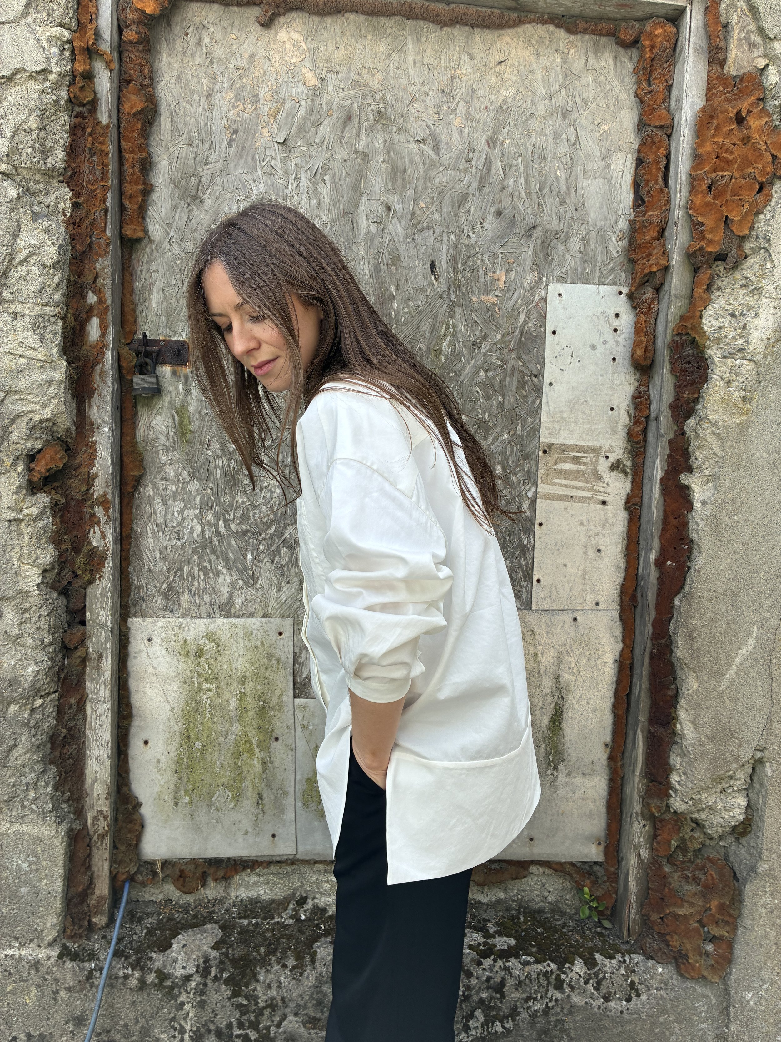 Side of Woman in front of wall wearing White 1st PAT-RN Woman Modula Shirt