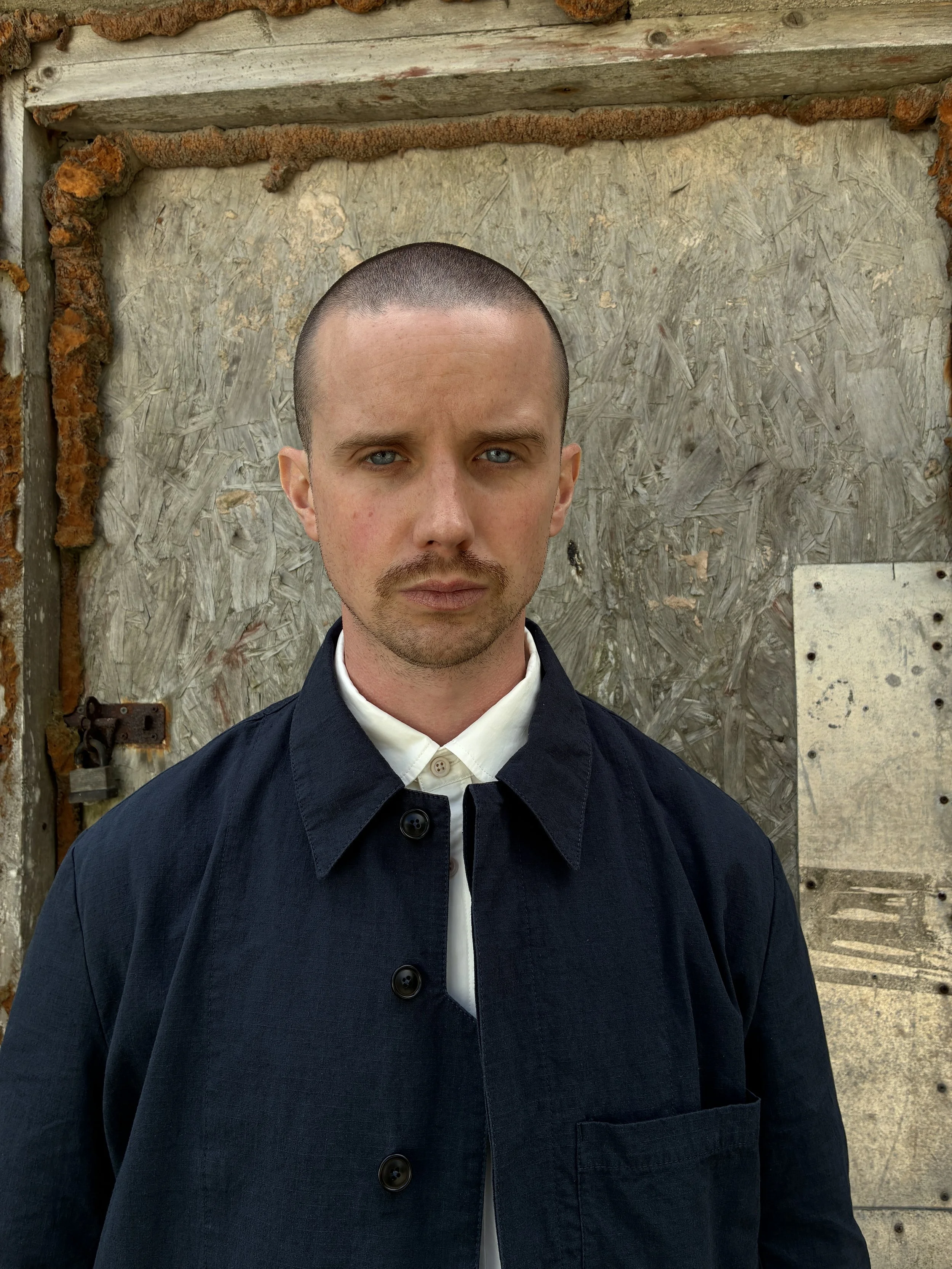 Closeup of Man in front of wall wearing 1st PAT-RN Navy Camden Jacket