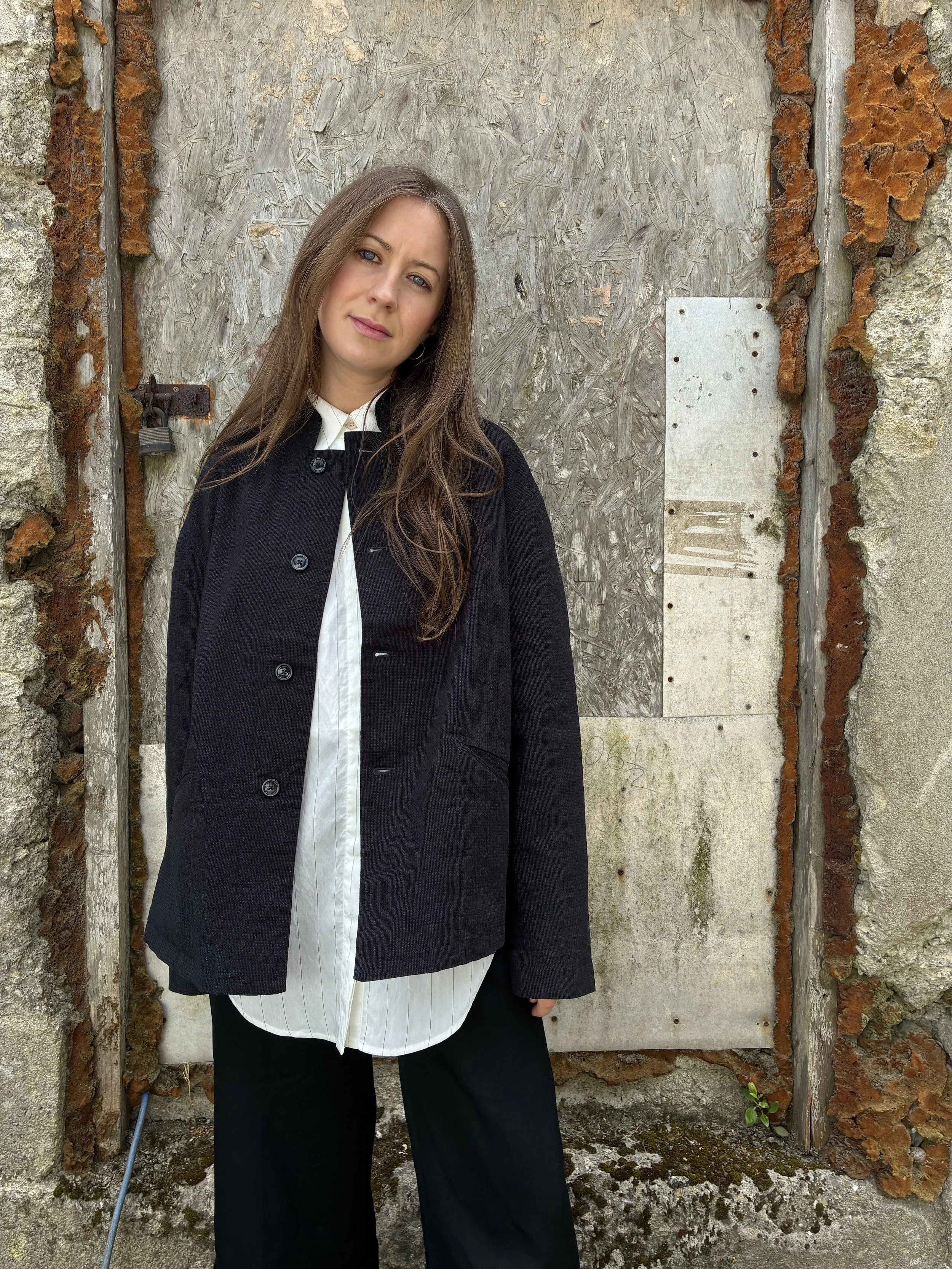 Woman in front of wall wearing Charcoal 1st PAT-RN Woman Rei Jacket