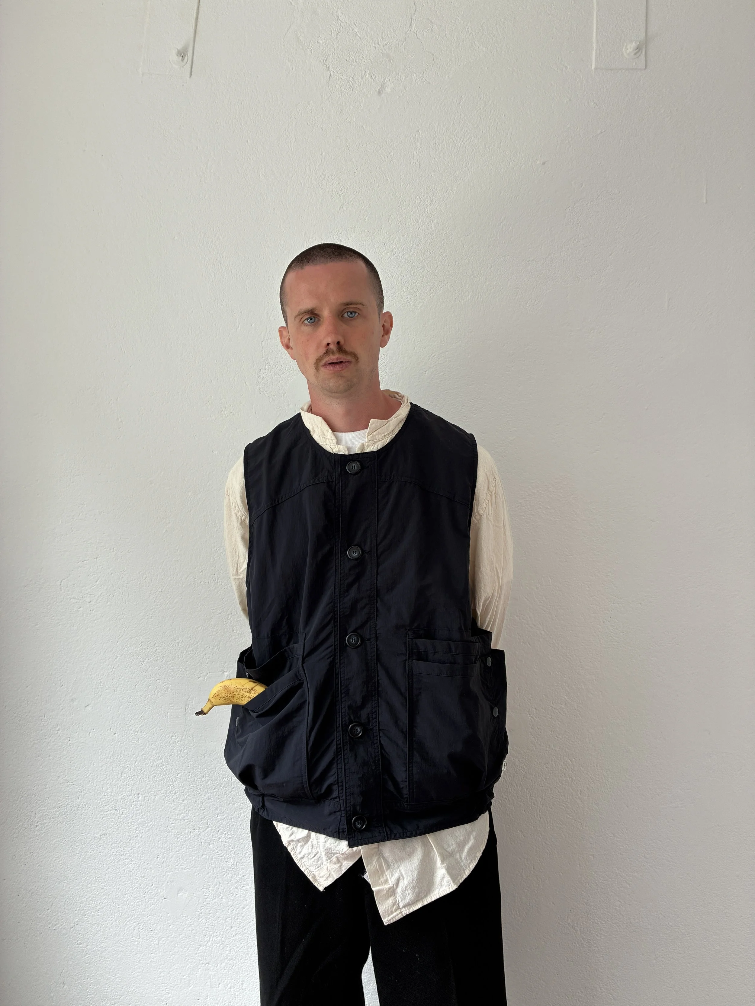 Man wearing Navy Sassafras Overgrown Hiker Vest with banana in pocket