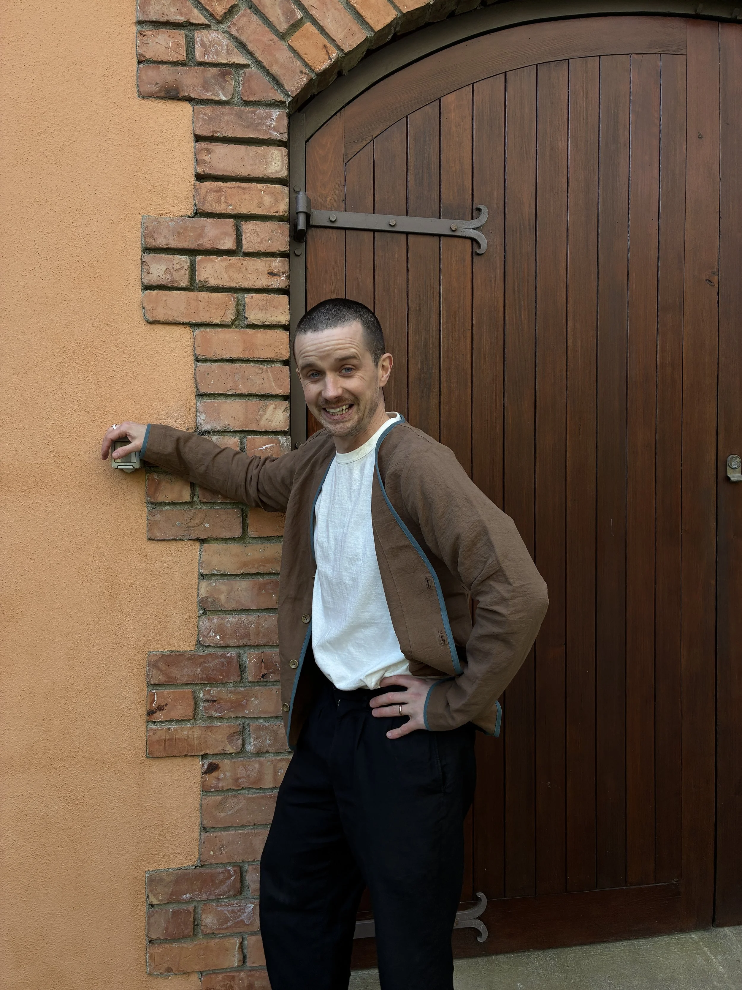 Man laughing leaning up against door in Frank Leder Linen Cotton Brown Teal Jacket