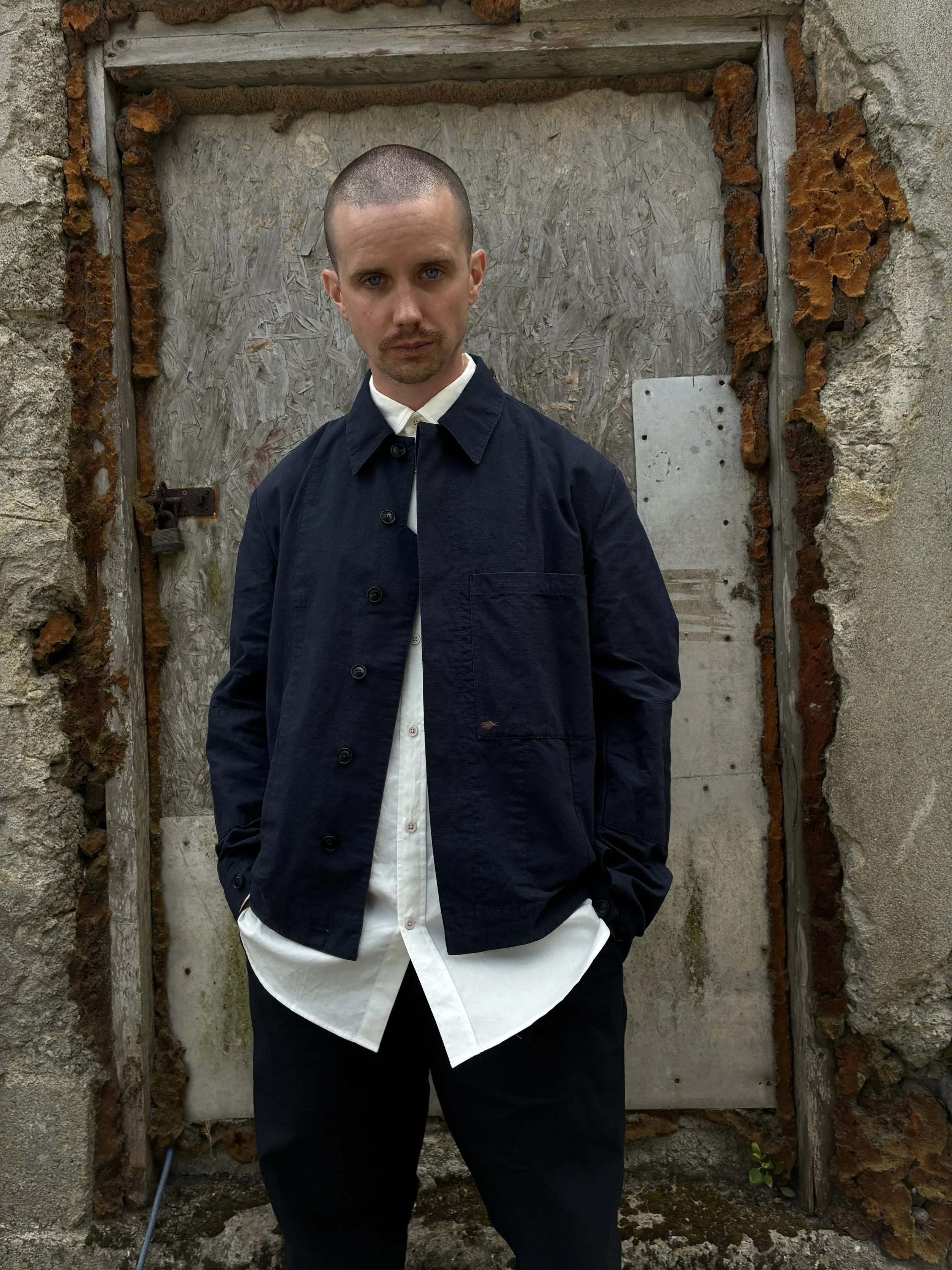 Man in front of wall wearing 1st PAT-RN Navy Camden Jacket unbuttoned