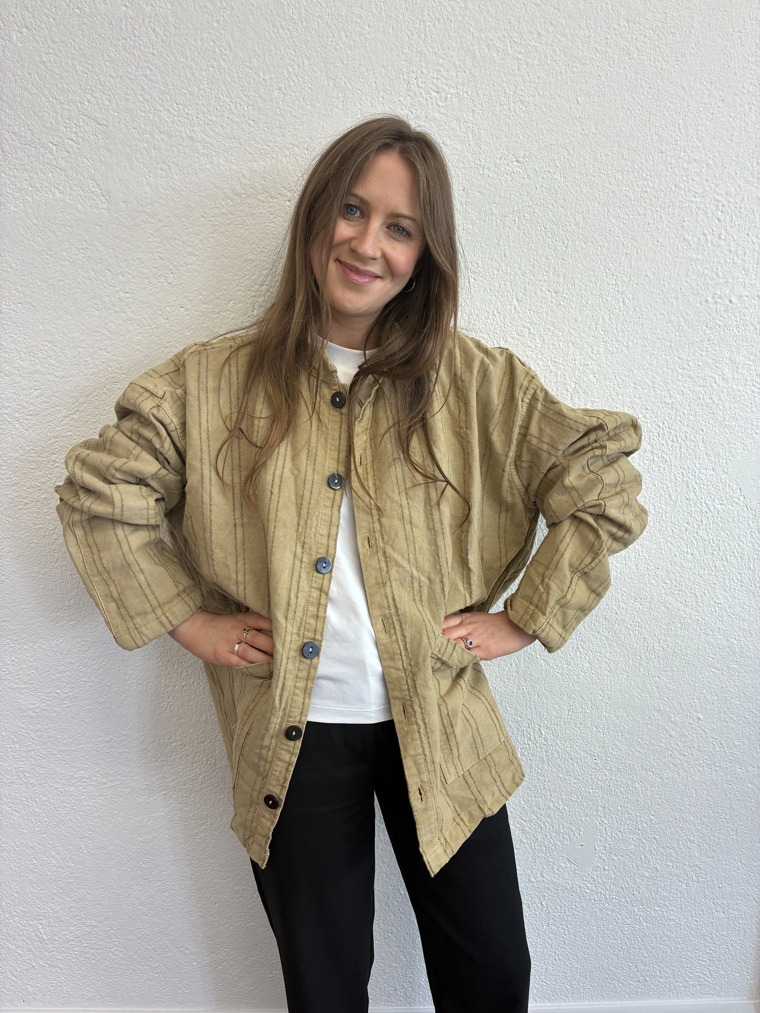Woman smiling wearing Drab Weld Tender Co Type 485 Isosceles Shirt in front of white wall