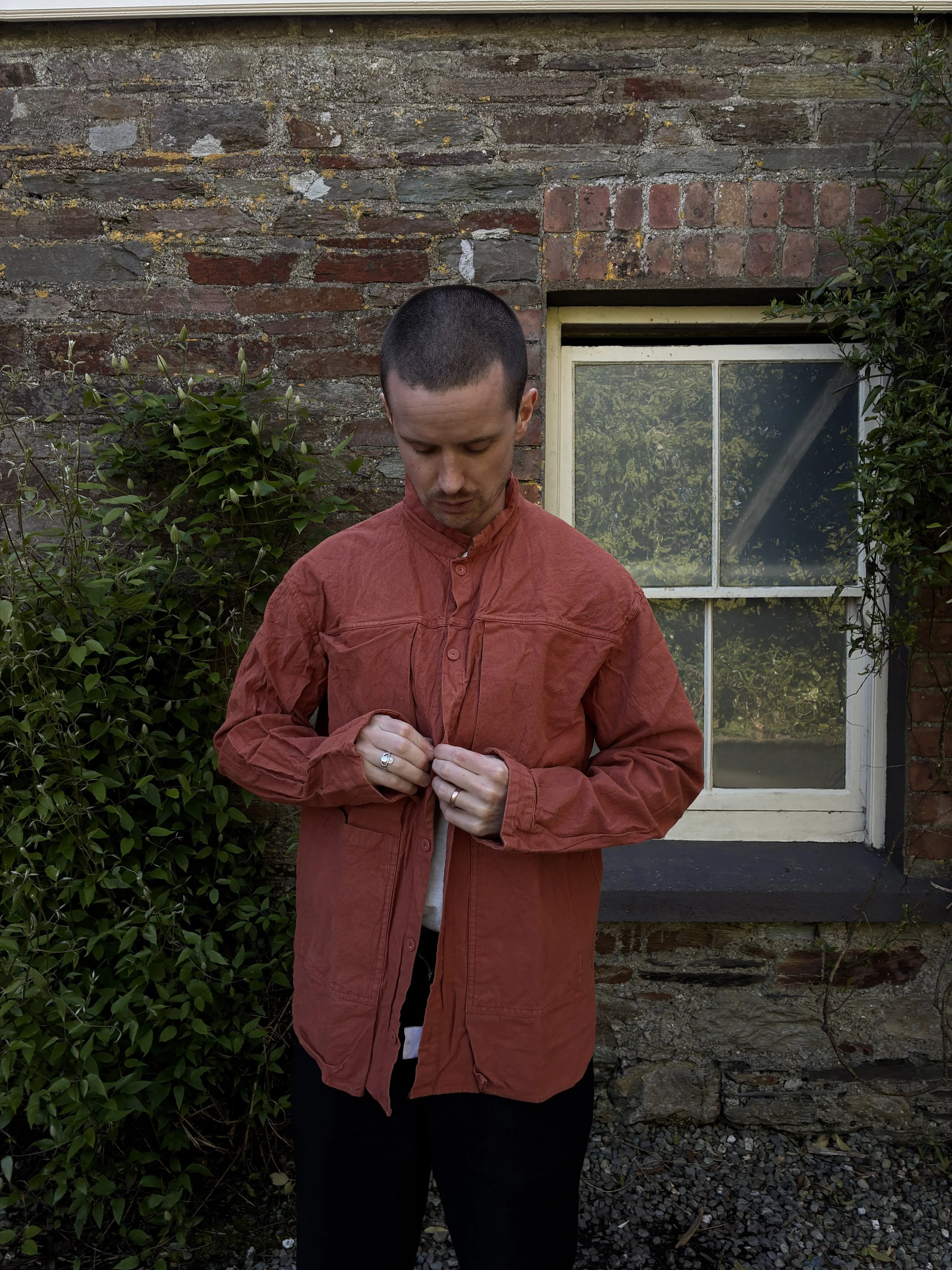 Man buttoning up orange Tender Co 402 Two Birds Shirt