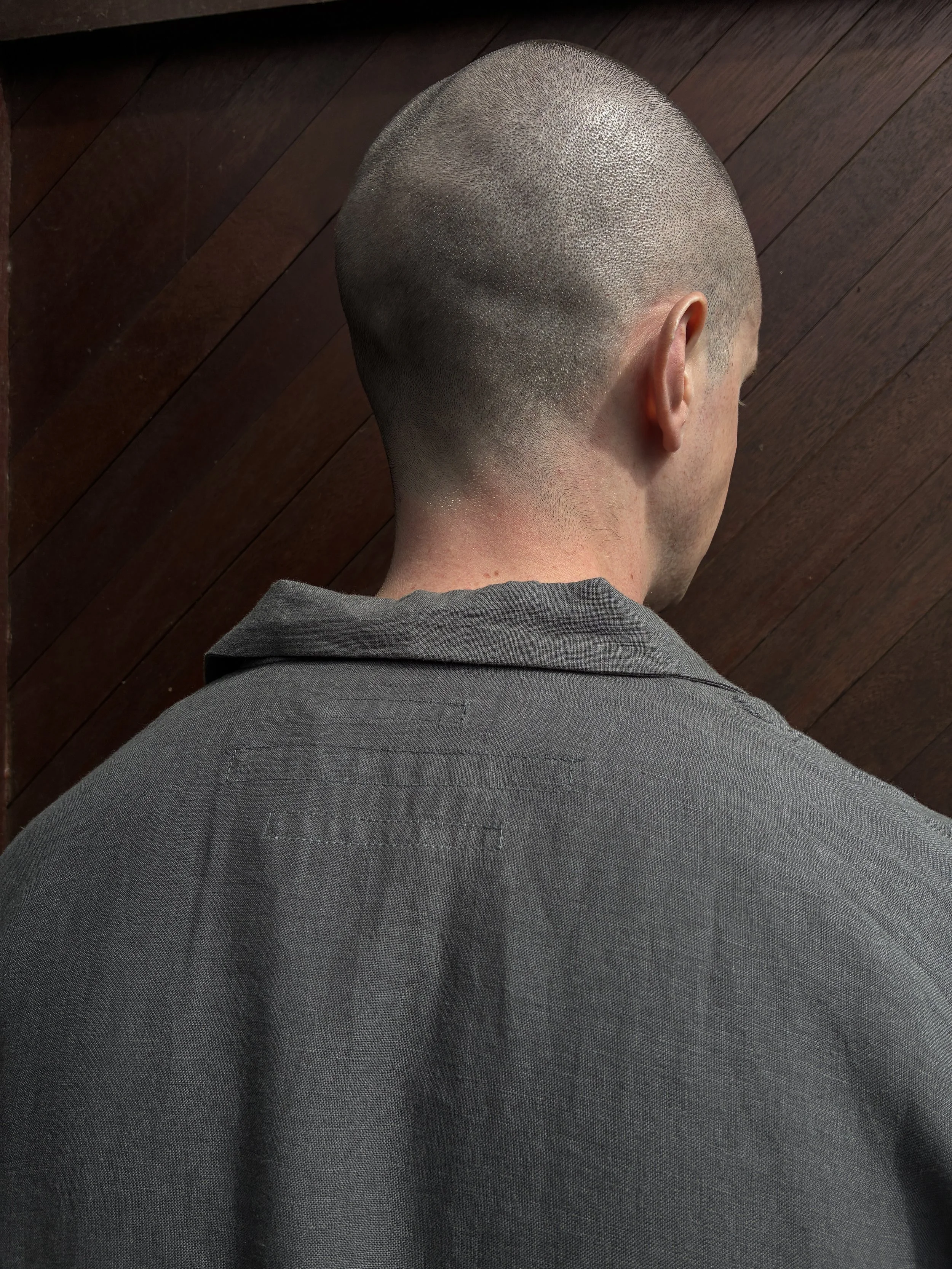 Close up of back of man in front of wooden door wearing Limited Edition Frank Leder Grey LINDWURM Linen Cardigan