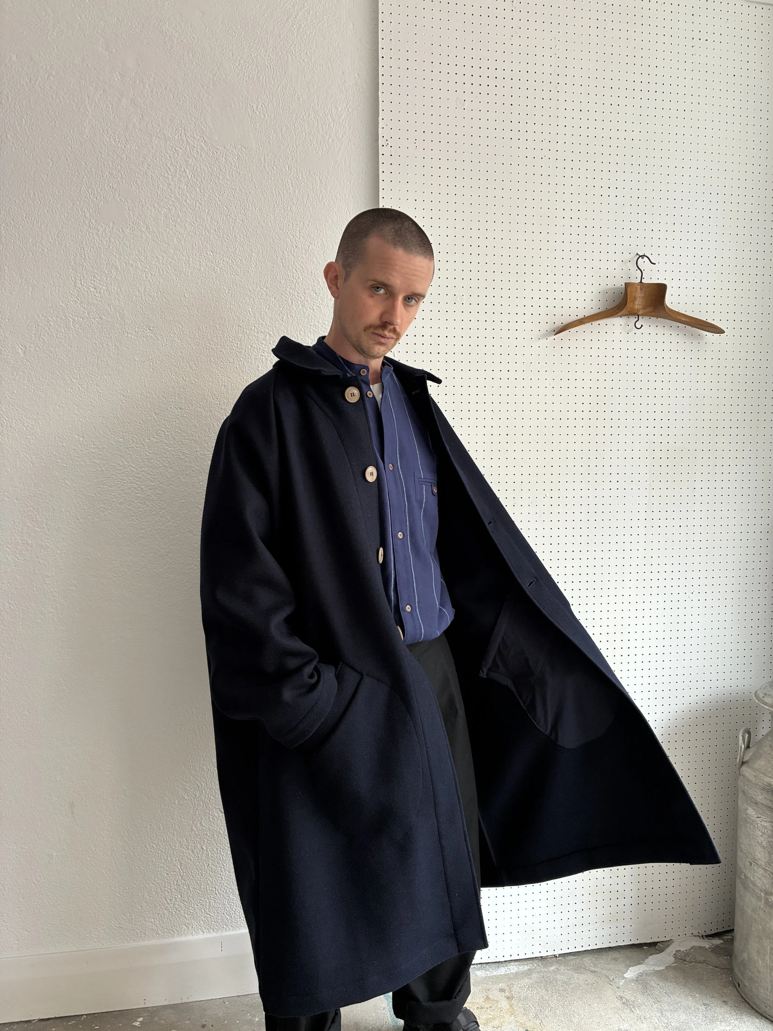 Model opening up Frank Leder Navy Wool Duster Coat, front profile view