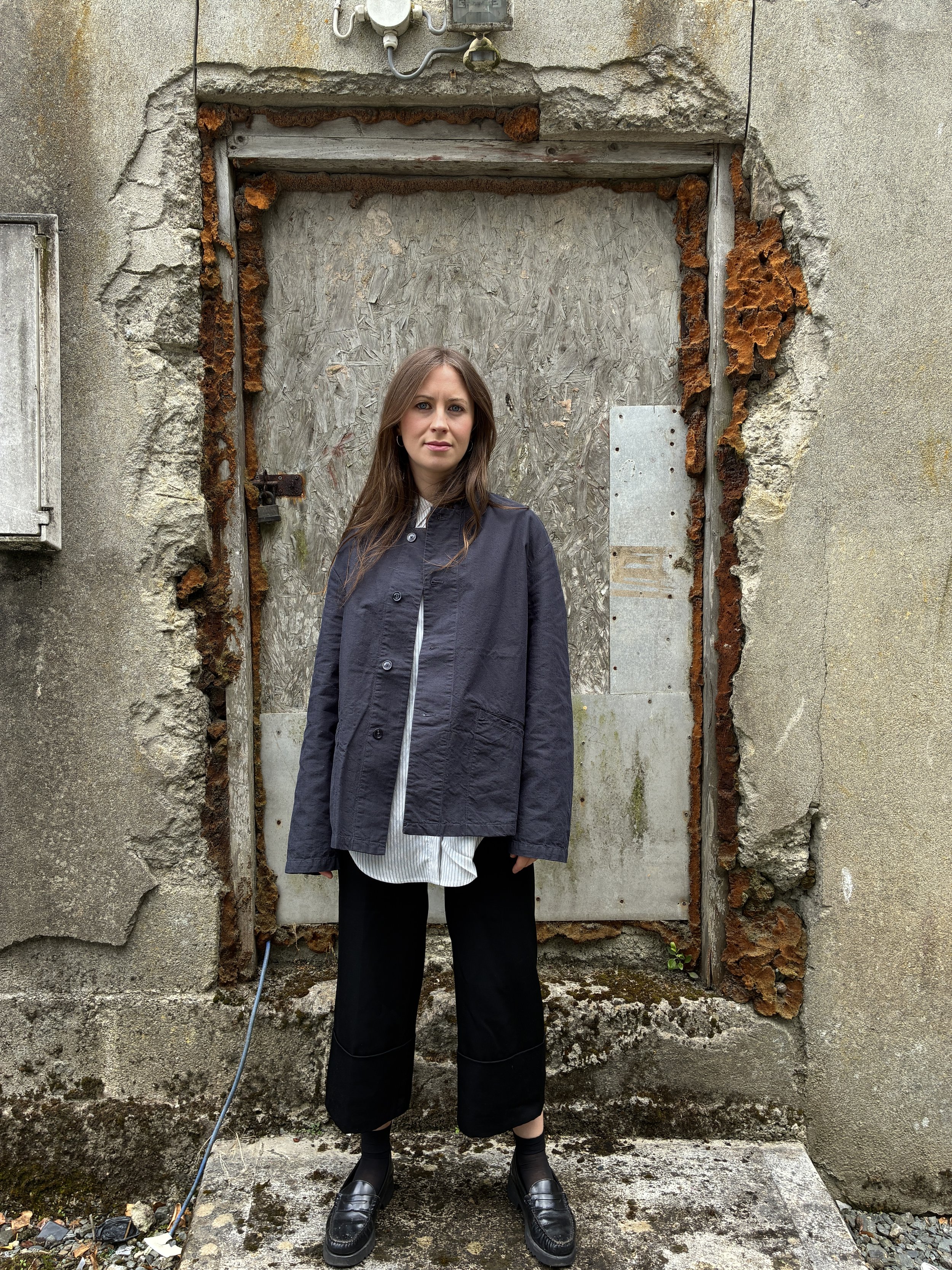 Woman in front of wall wearing Navy 1st PAT-RN Woman Rei Jacket