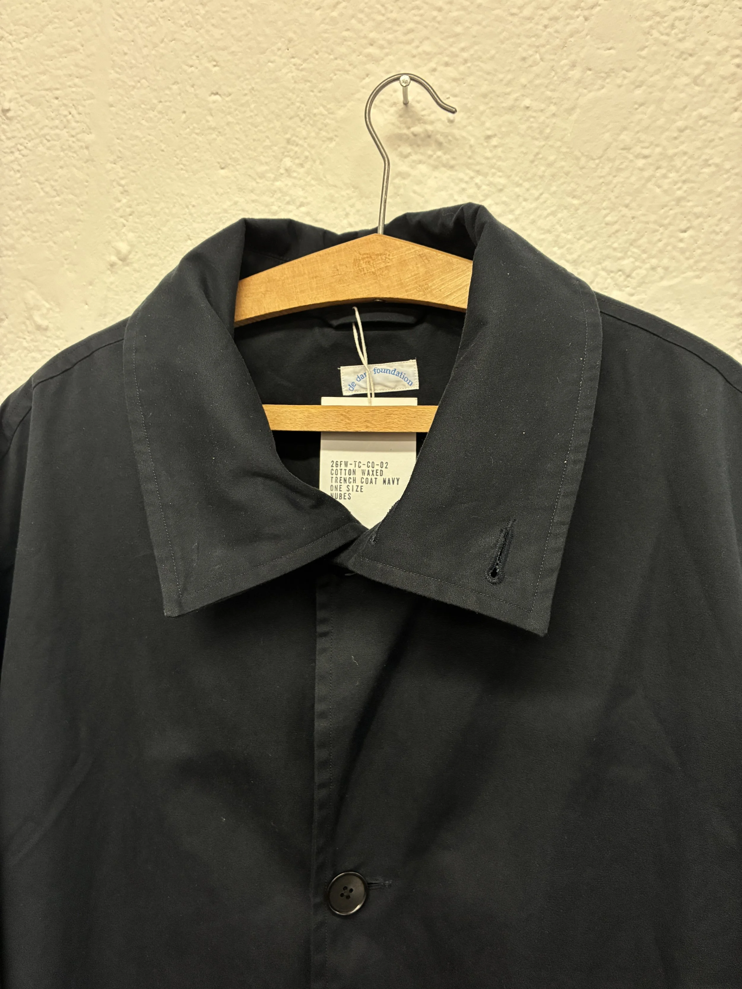 Closeup of folded collar of Navy De Dam Foundation Cotton Gabardine Trench Coat on hanger