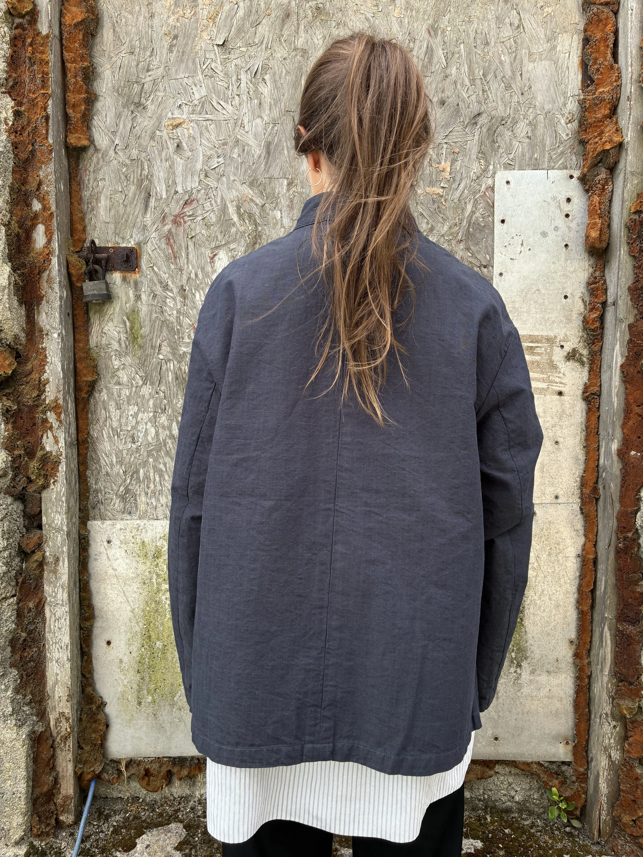 Back of Woman in front of wall wearing Navy 1st PAT-RN Woman Rei Jacket