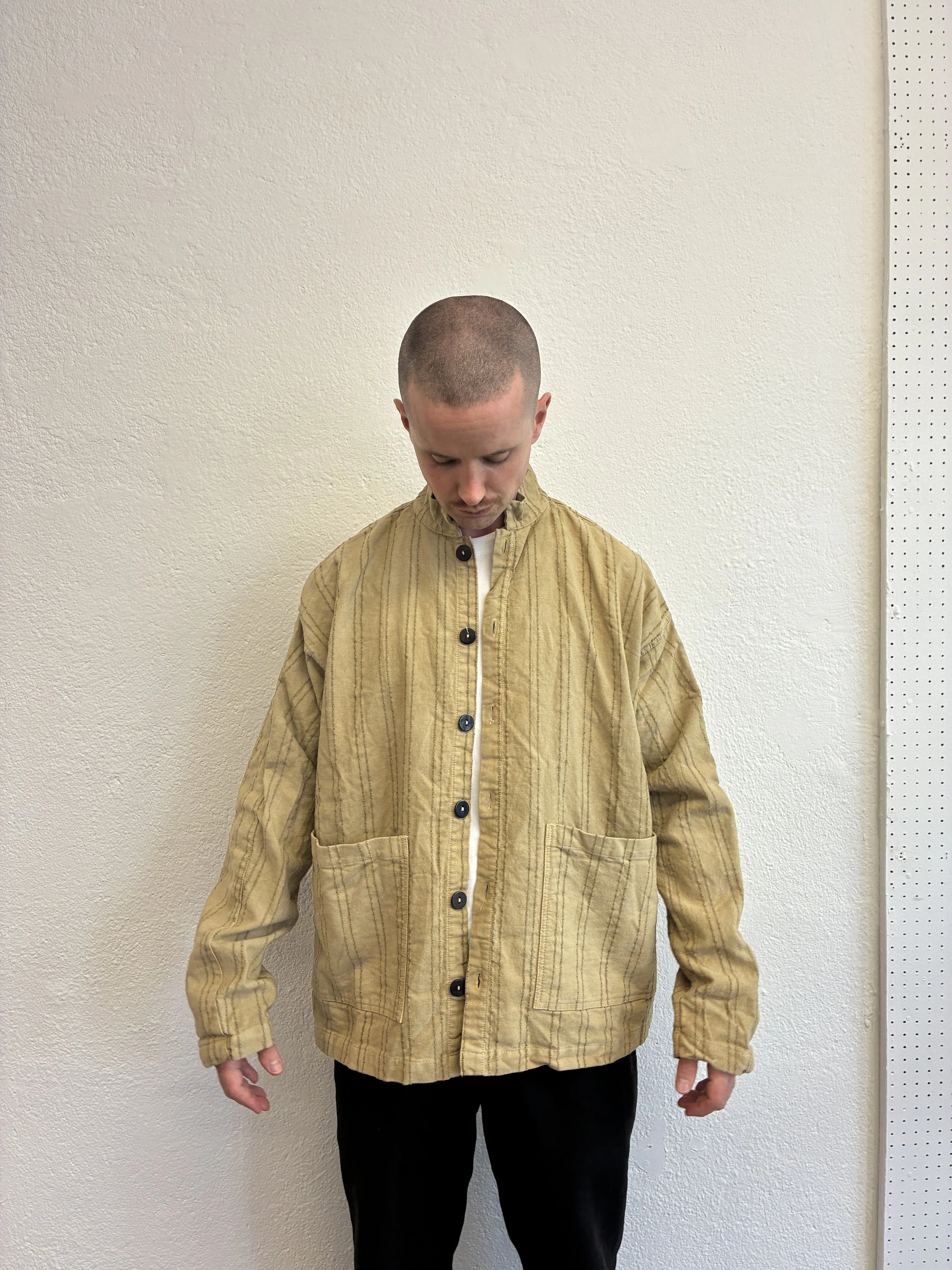 Man wearing unbuttoned Drab Weld Tender Co Type 485 Isosceles Shirt in front of white wall