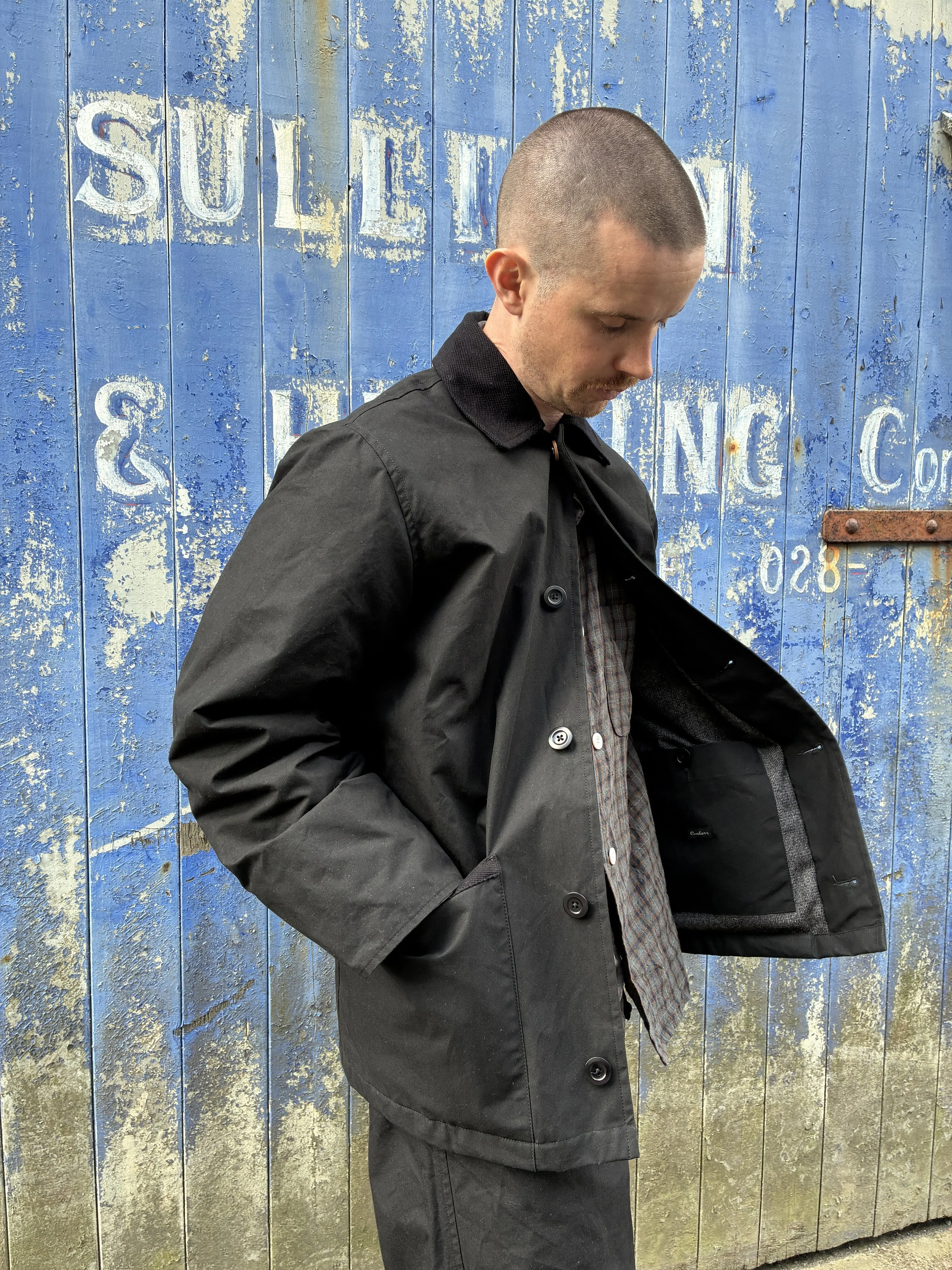 Man wearing Black Conkers Blanket Jacket in front of blue graffiti