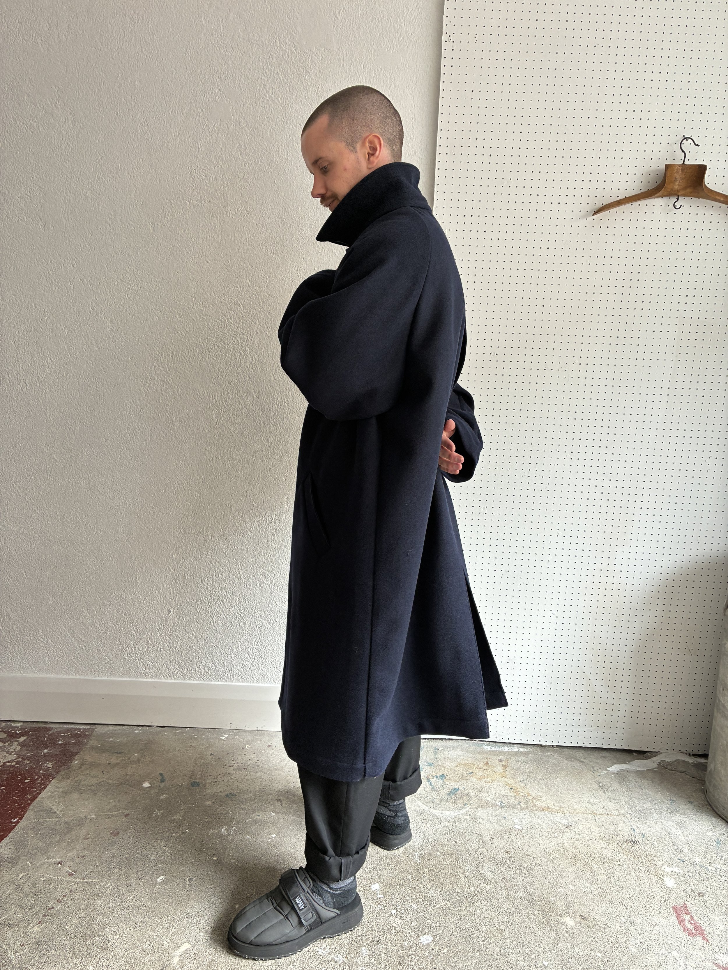 Model wears Frank Leder Navy Wool Duster Coat, side profile view