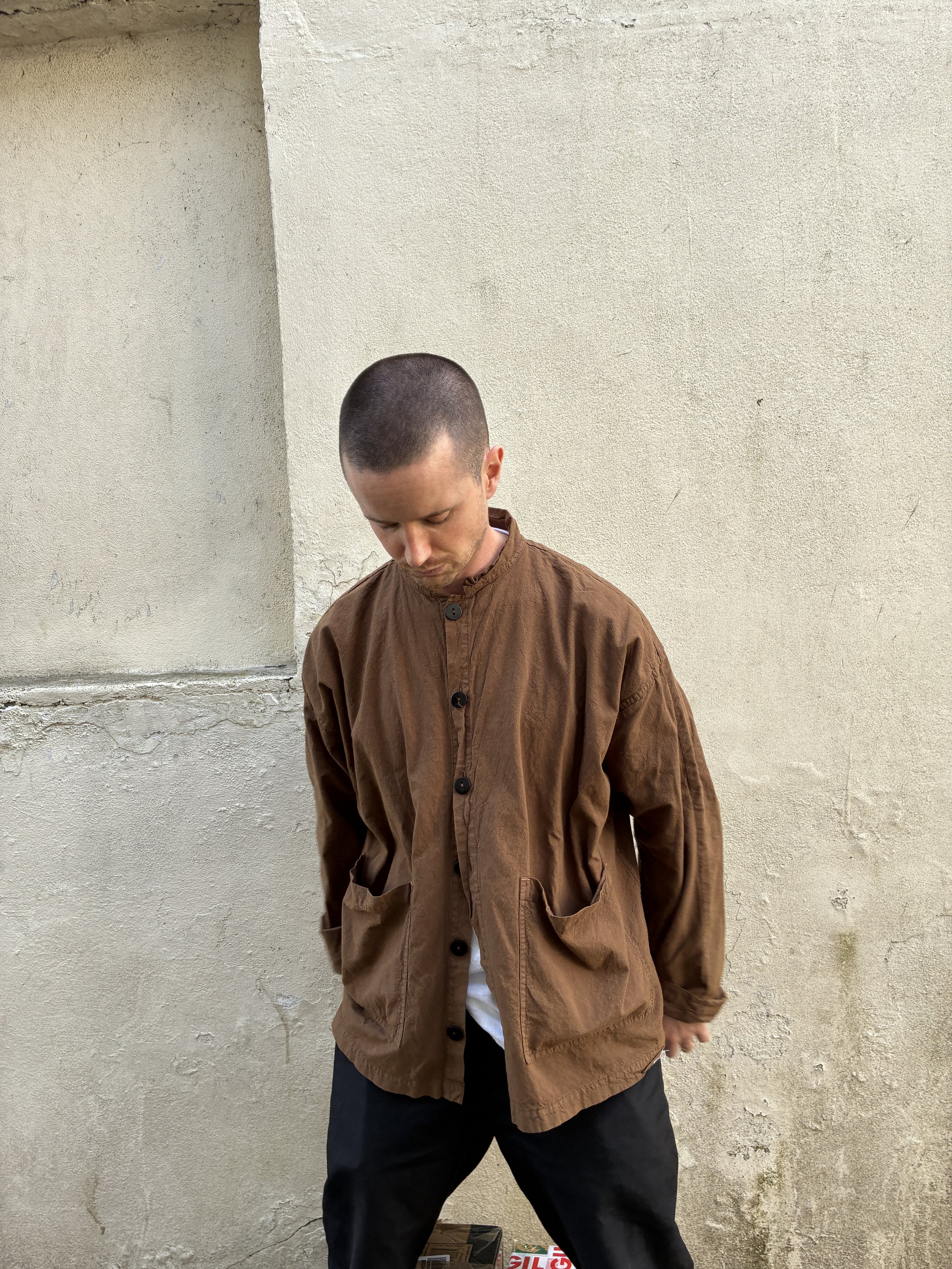 Man looking down at ground wearing Tender Co Type 485 Isosceles Brown Hat Shirt