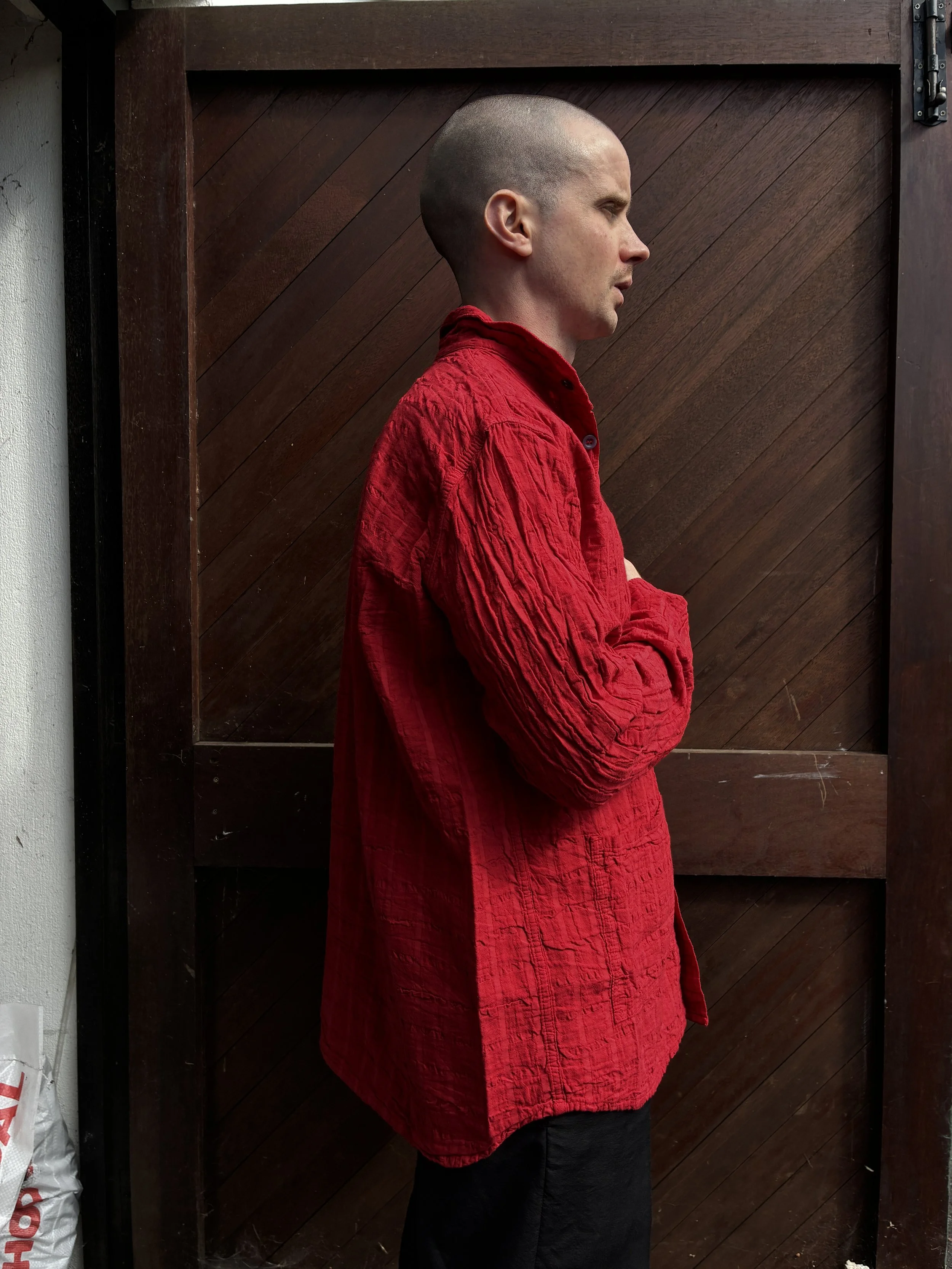 Side of man in front of wooden door wearing Red Tender Co. 468 Flipped Collar Shirt