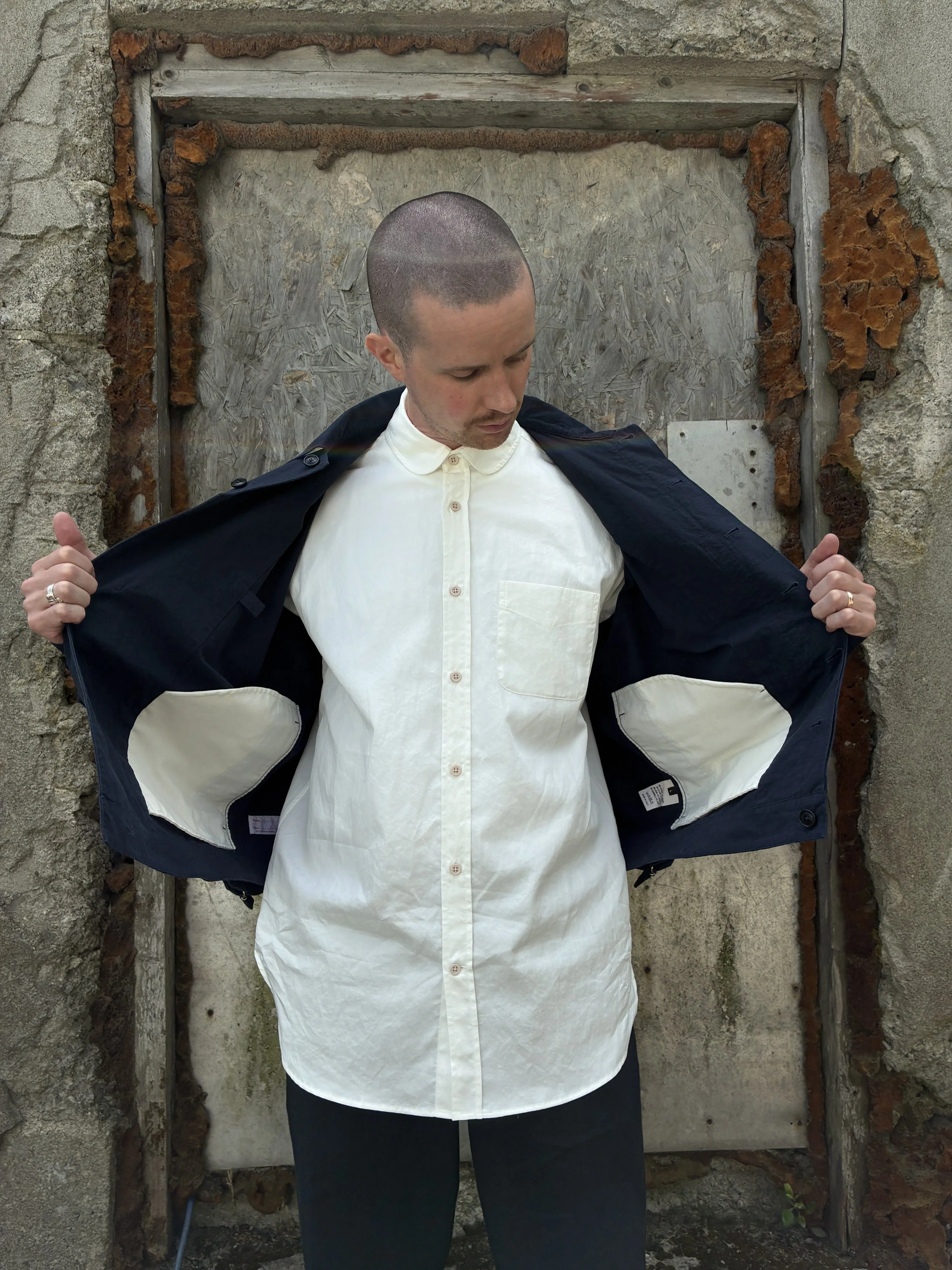 Man in front of wall opening up 1st PAT-RN Navy Camden Jacket