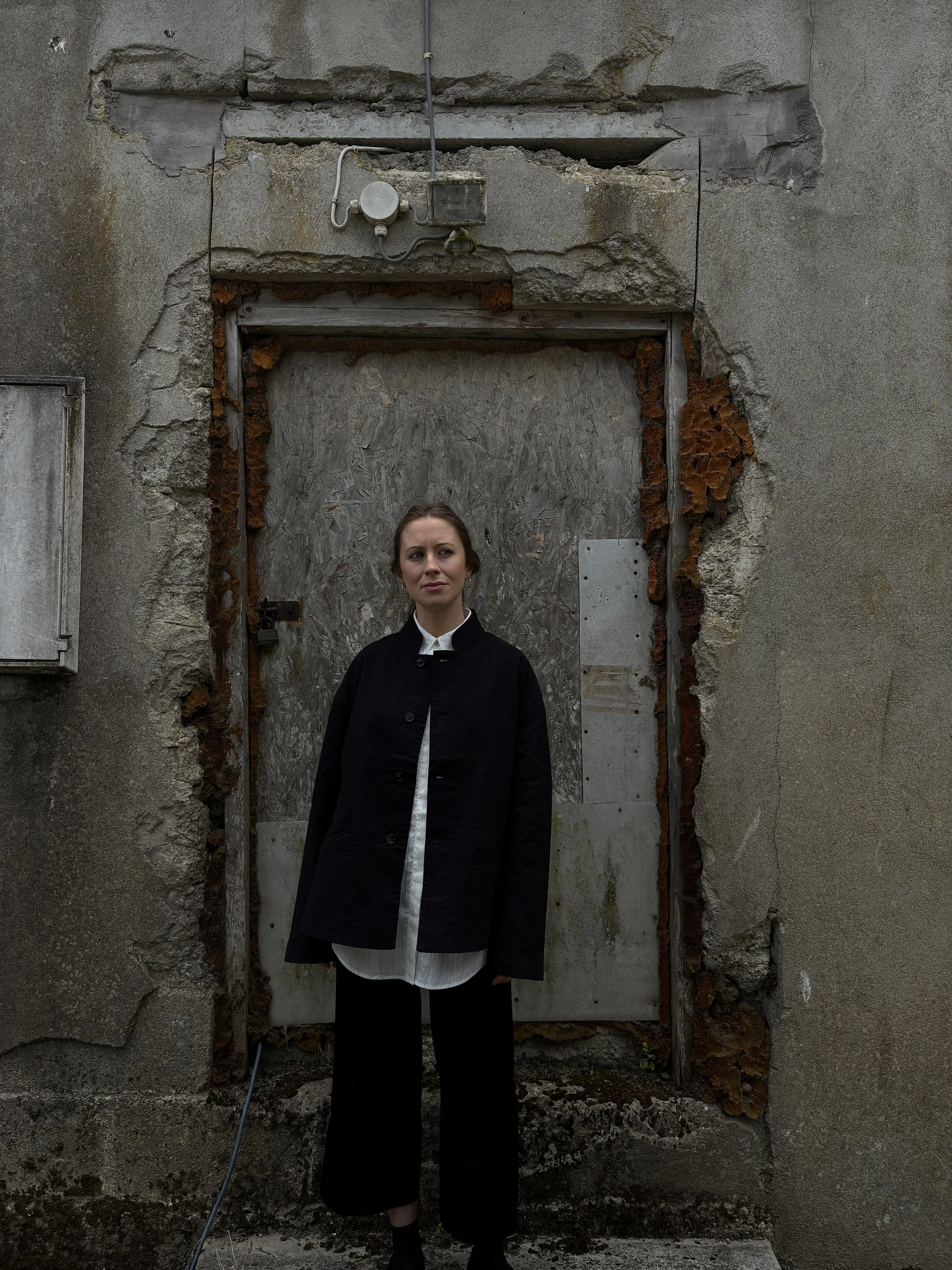 Woman in front of wall wearing Charcoal 1st PAT-RN Woman Rei Jacket