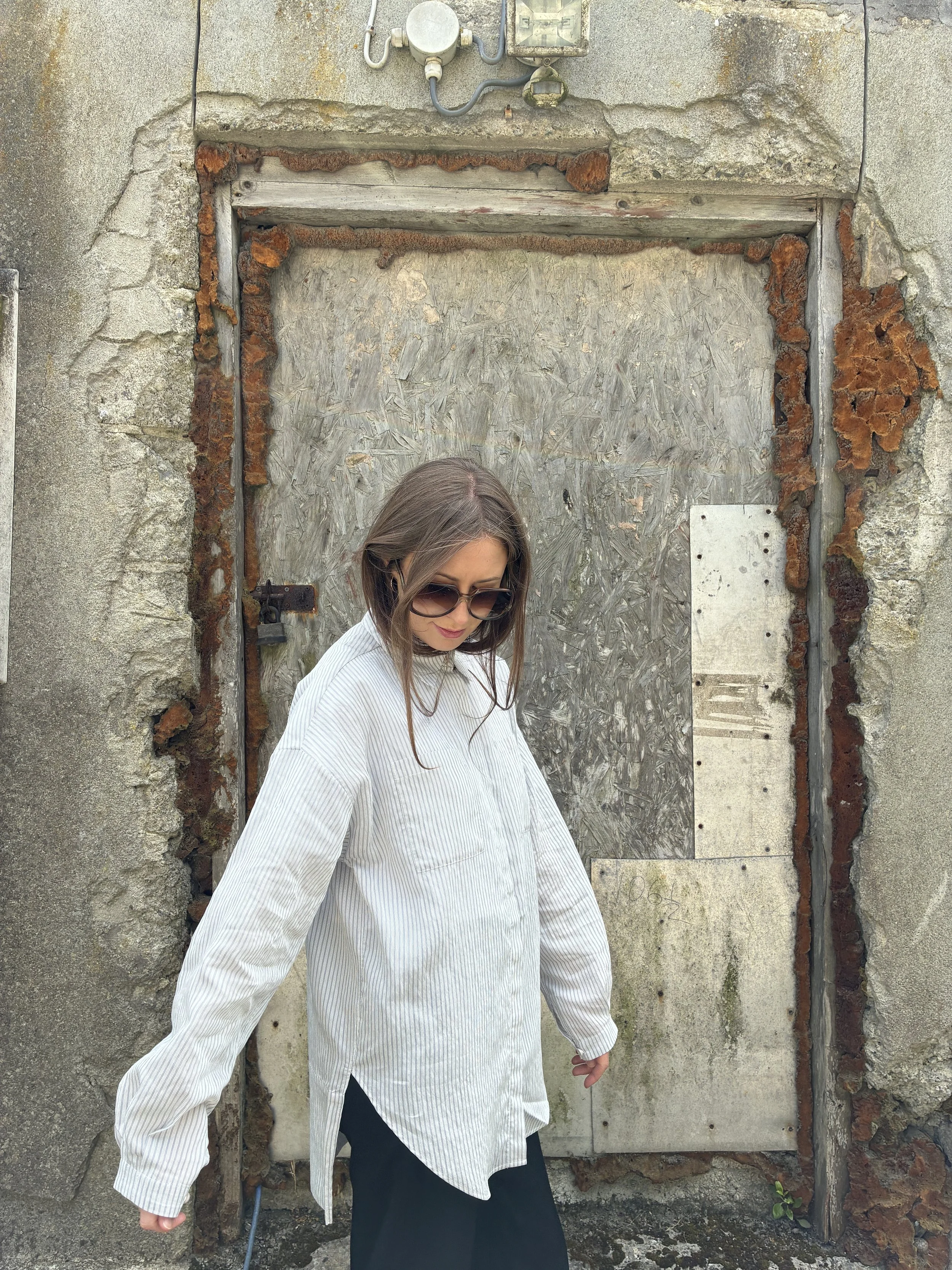 Woman in front of wall looking at ground wearing 1st PAT-RN Woman Modula Shirt in Fine Stripes
