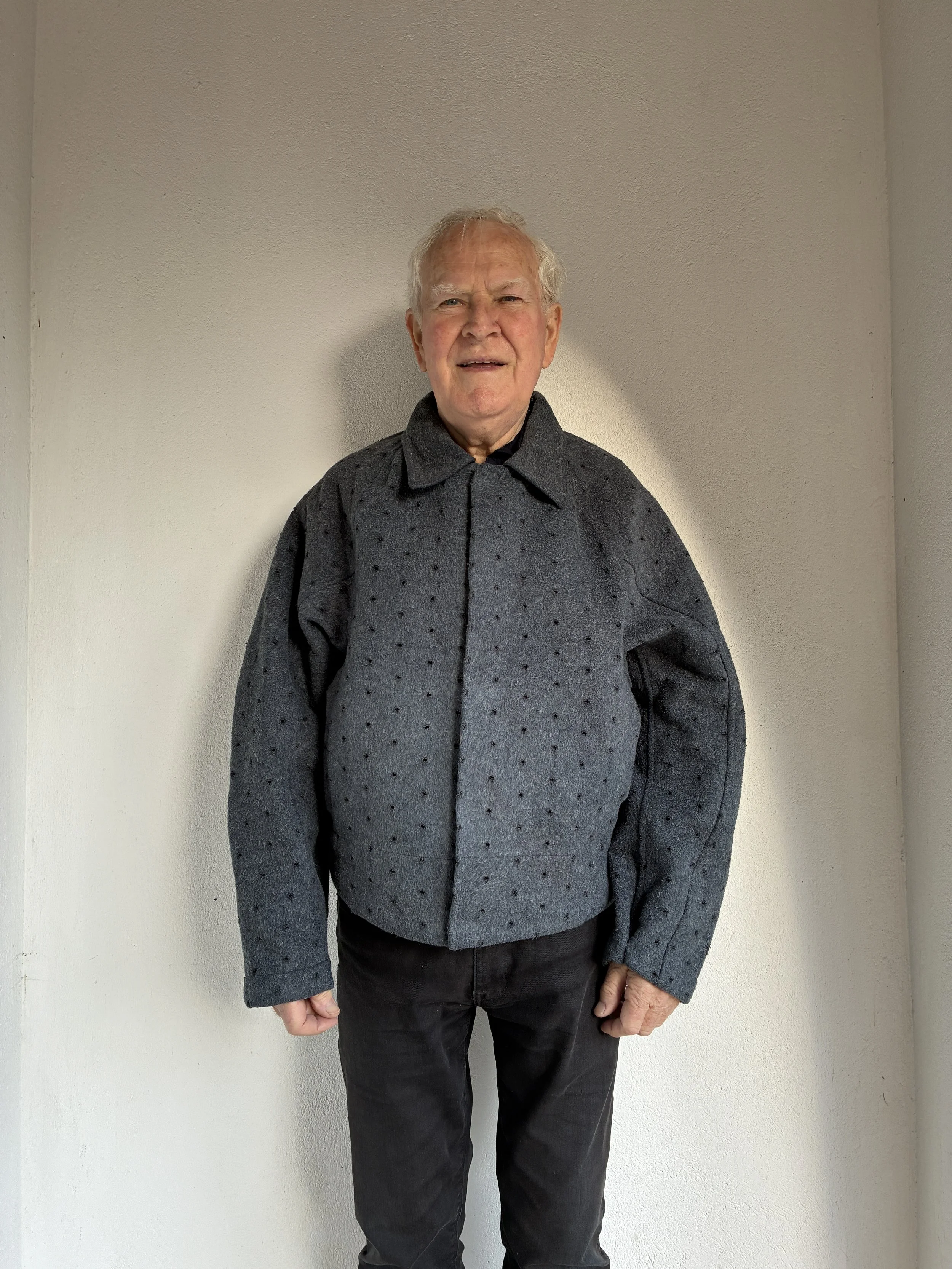 Man smiling outside wearing Middle Distance grey Drill jacket