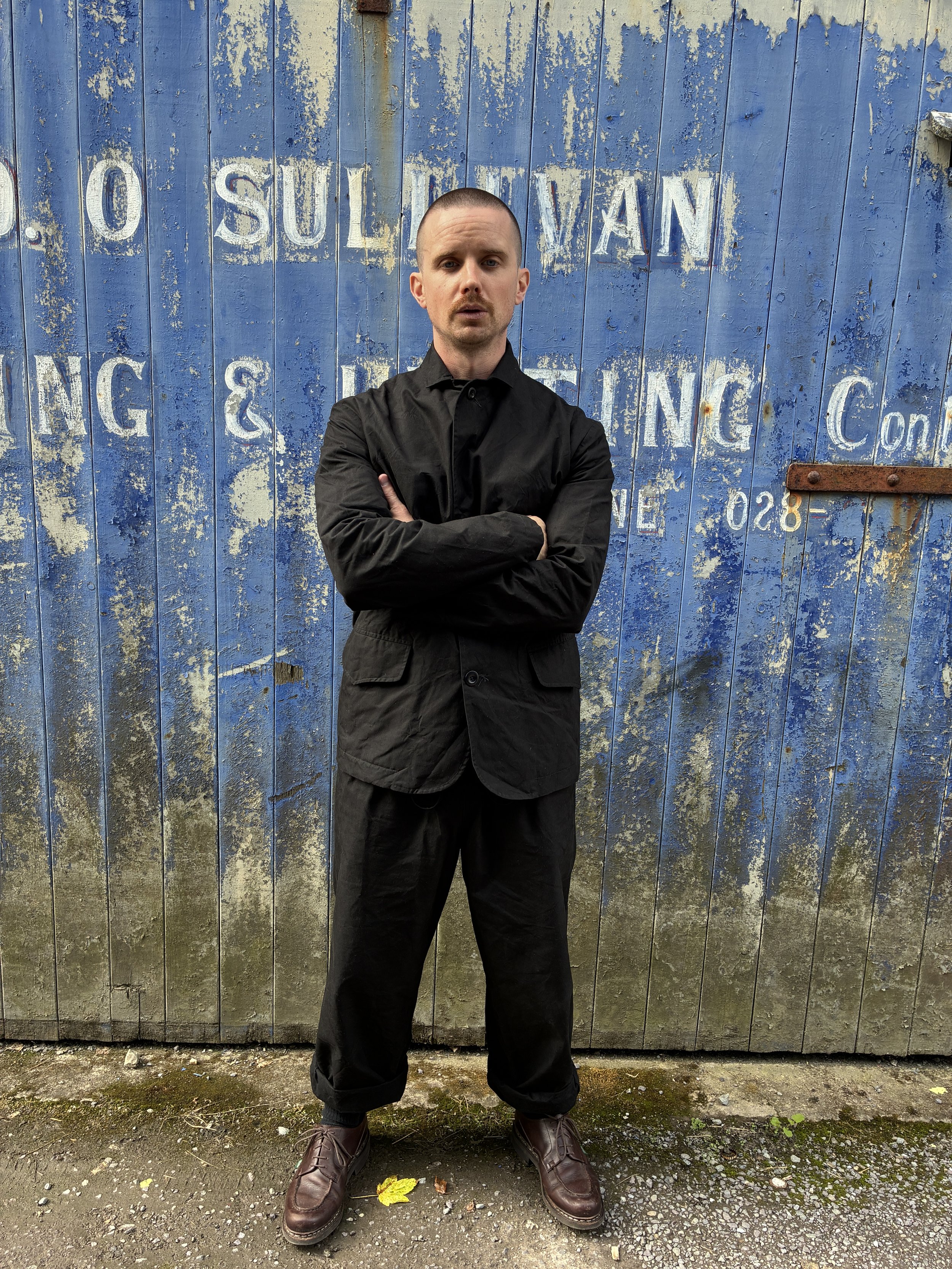 Man with arms folded in Conkers Rambler Black Waxed Cotton Trousers and blazer