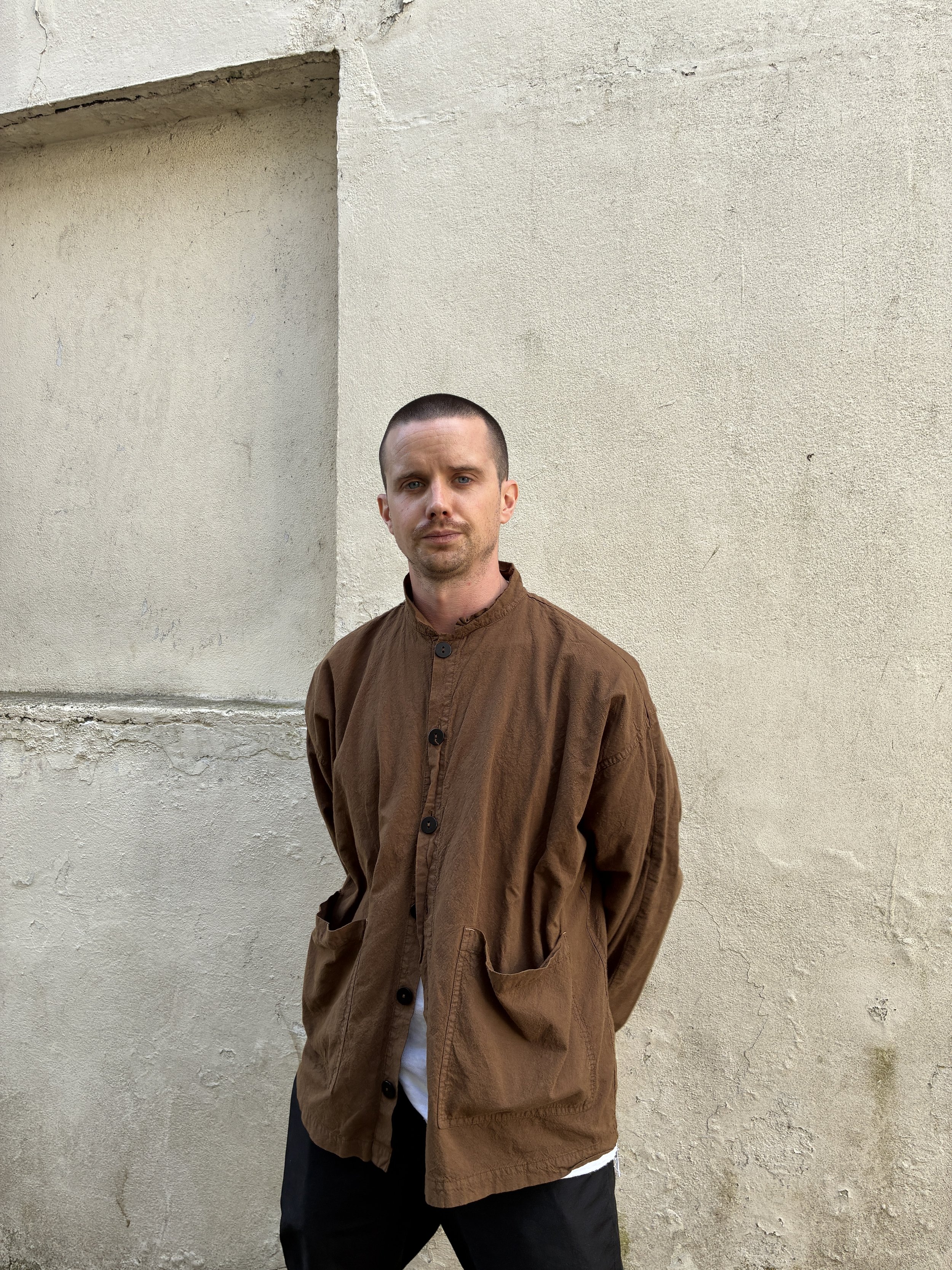 Man in front of wall wearing Tender Co Type 485 Isosceles Brown Hat Shirt